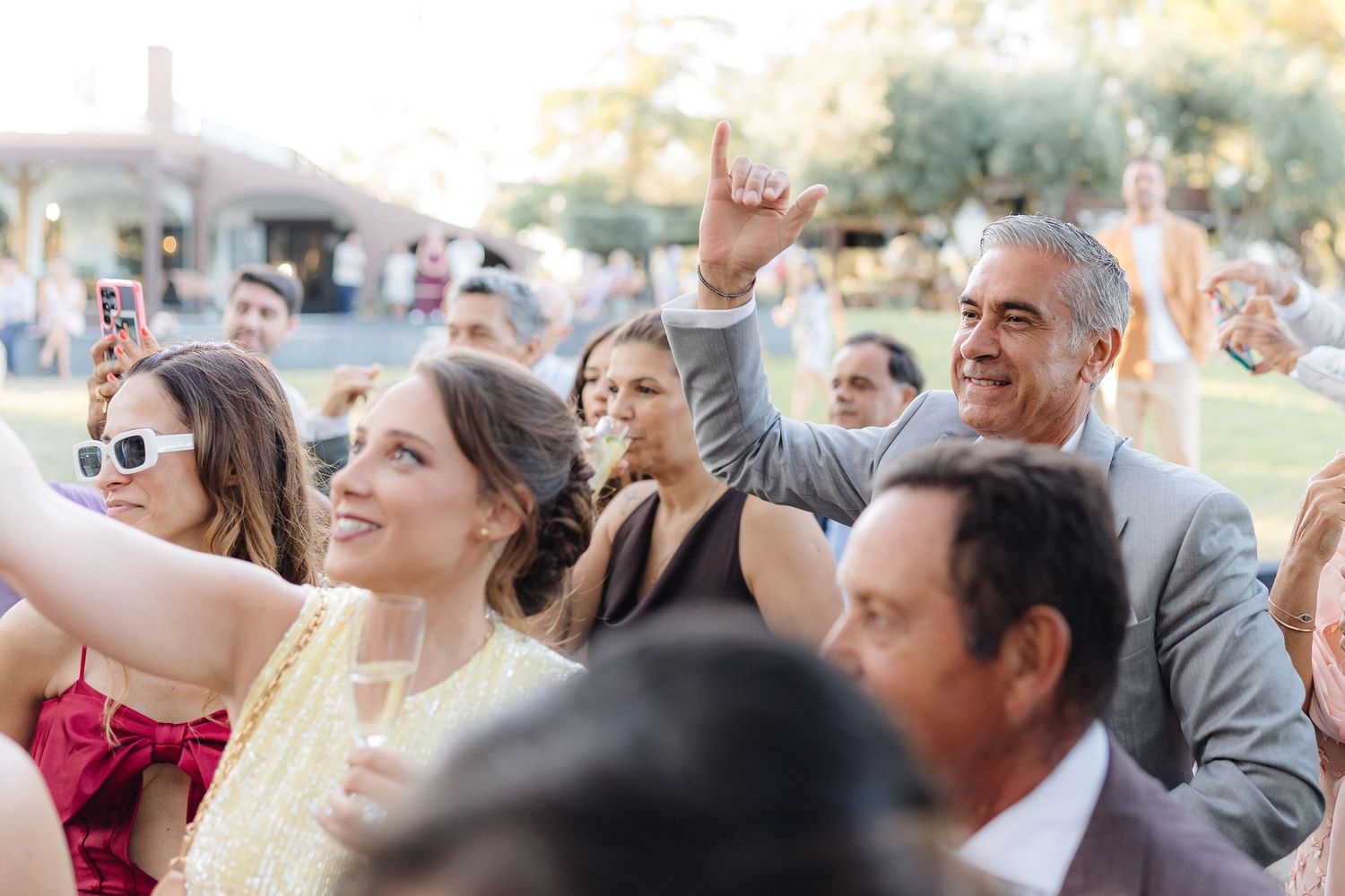 Wedding guests dancing with hands raised during sunset celebration.