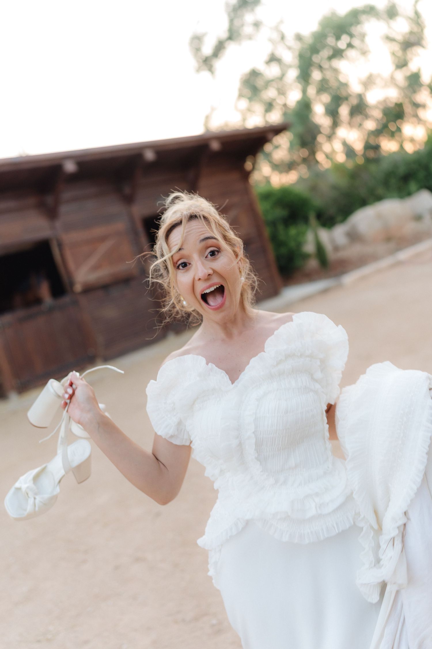 A person in a white dress twirls playfully outdoors.