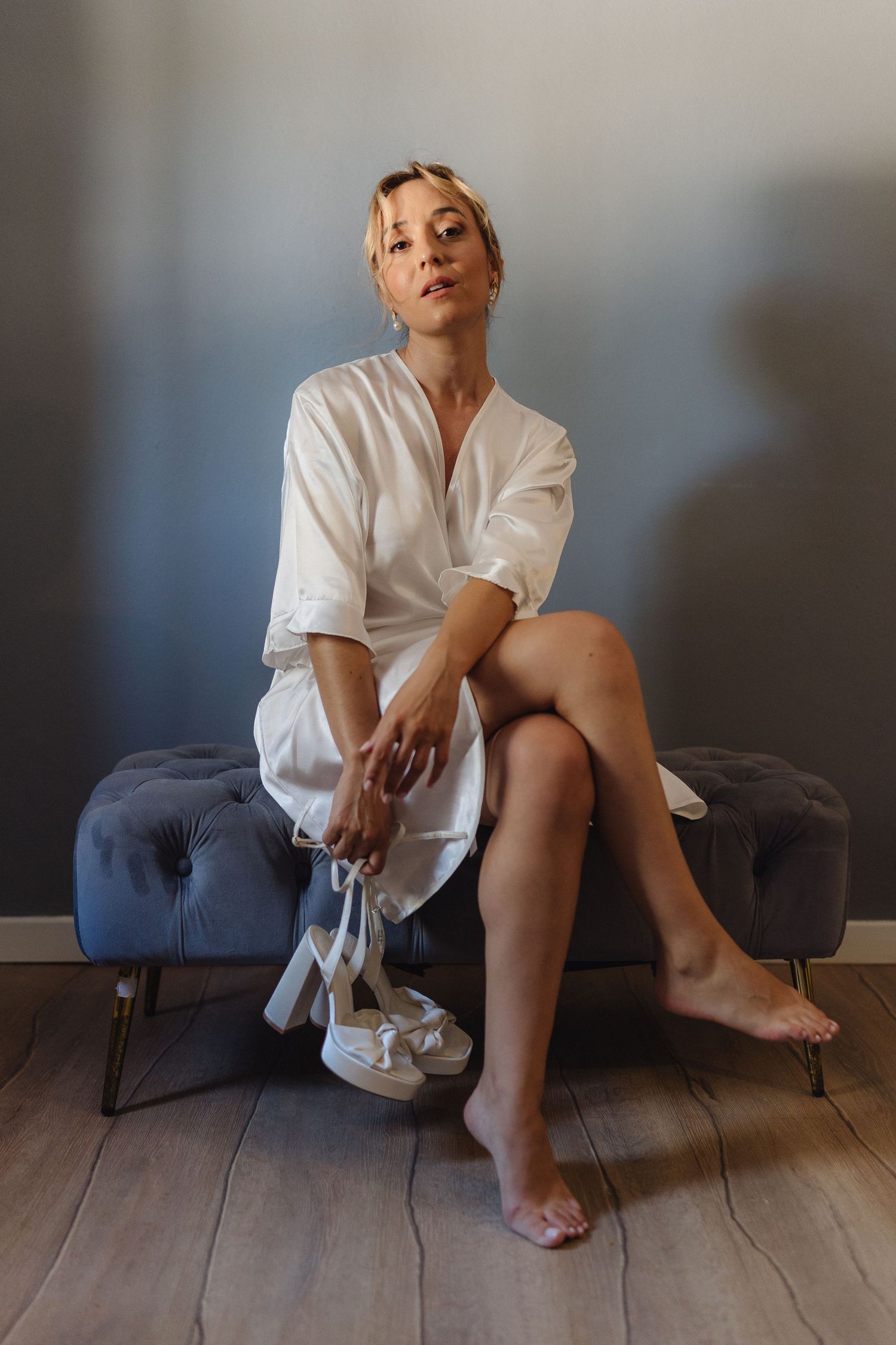 Person in white button-down shirt sits relaxed on dark couch against grey wall.
