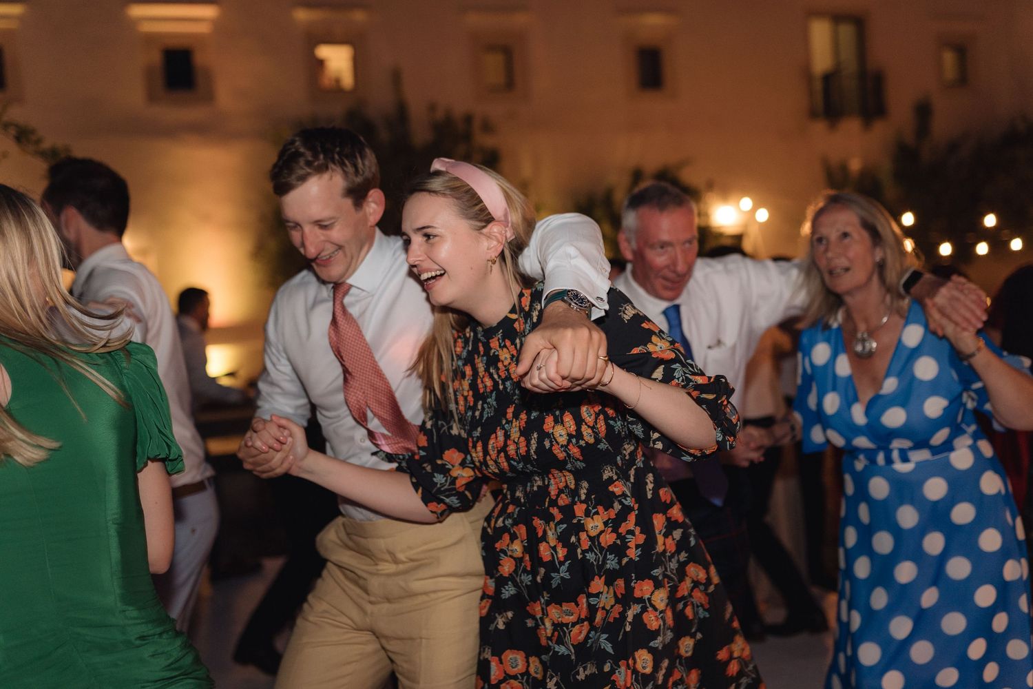 Wedding guests enjoying themselves on the dance floor with string lights overhead.