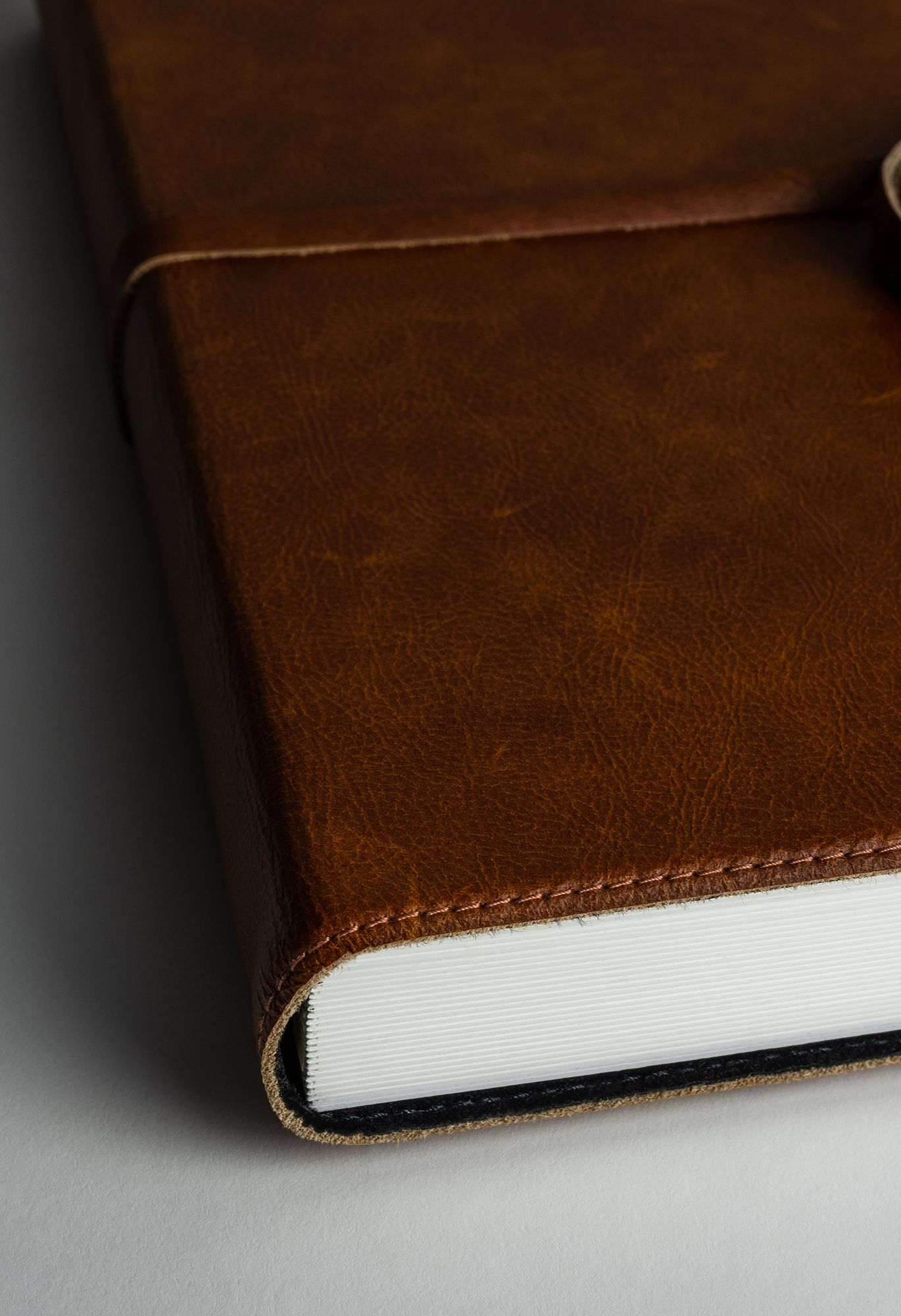Close-up macro shots showing the spine and binding details of a brown leather book or journal.