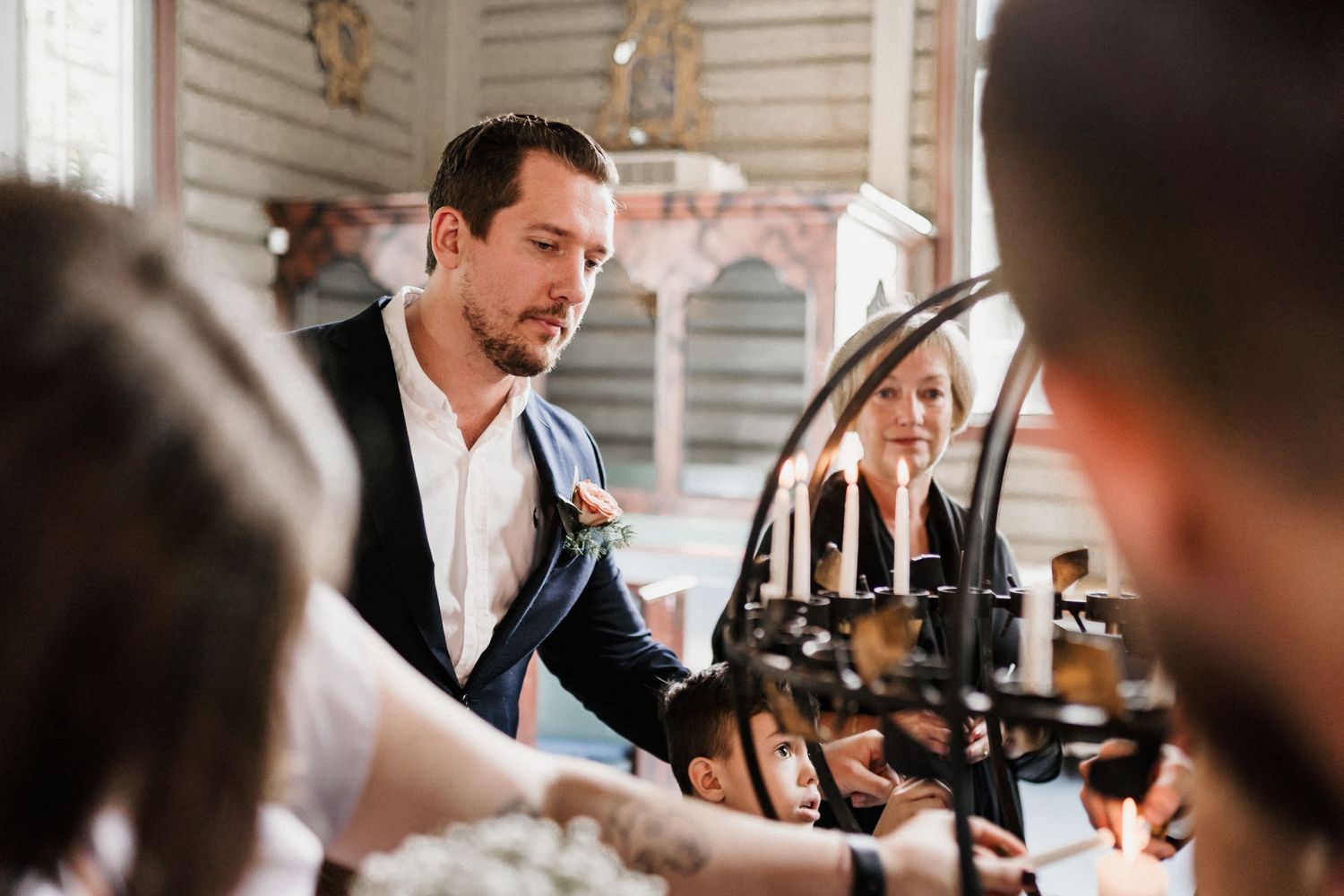 Wedding guests gather around tables at an indoor reception venue.