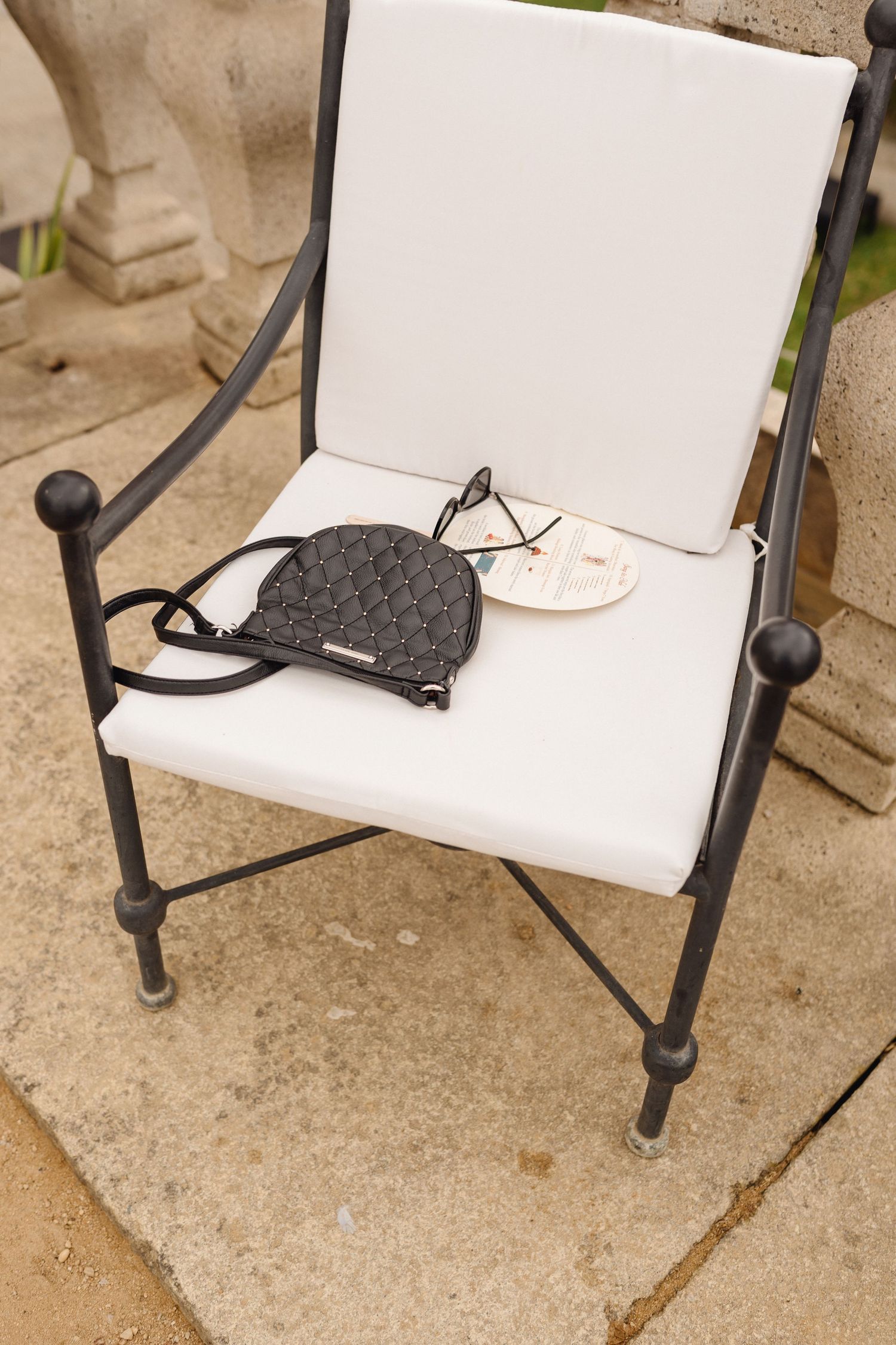 A series of white outdoor patio chairs with black metal frames arranged against a concrete surface.