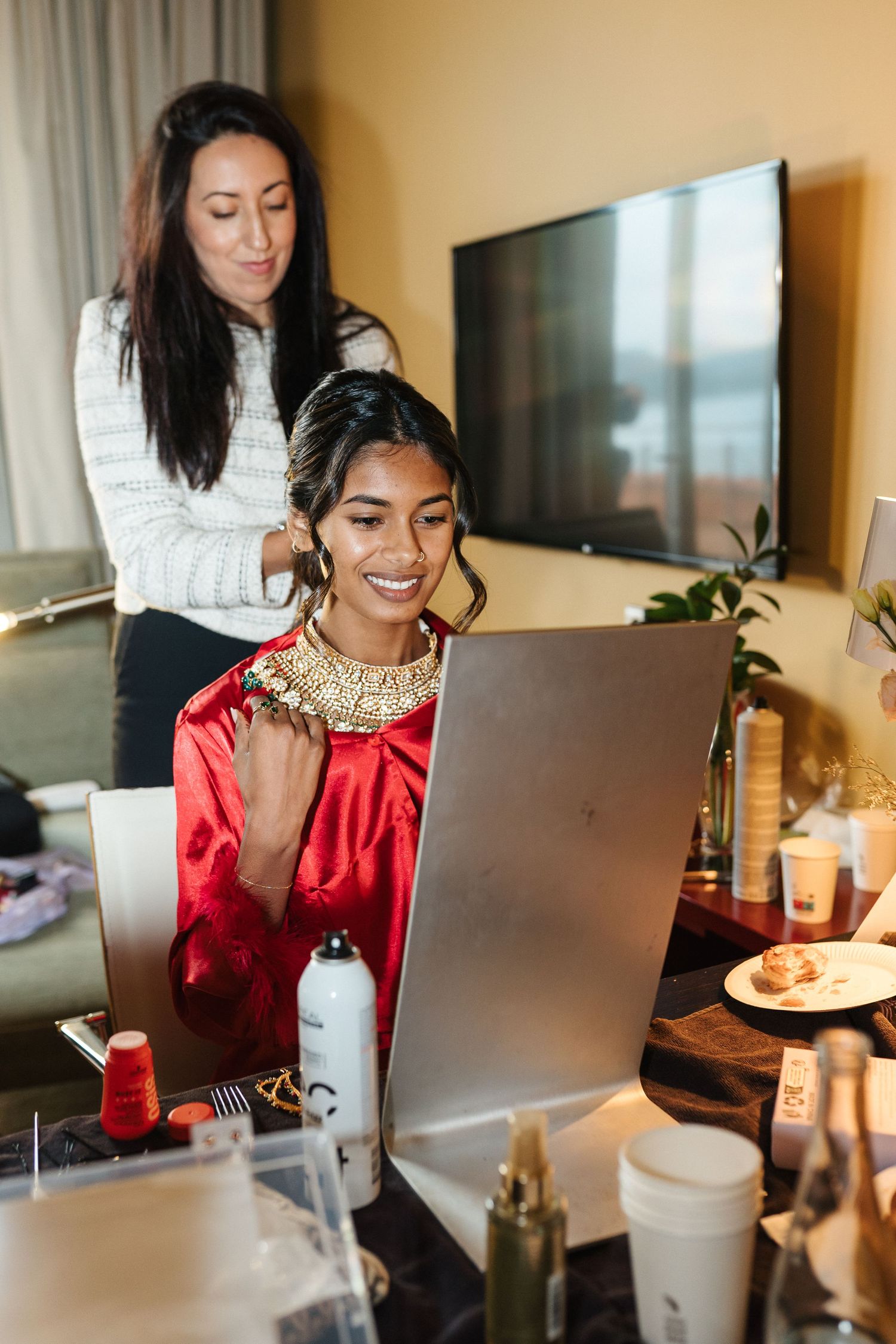 Getting ready scene with laptops and makeup preparations in warm lighting.