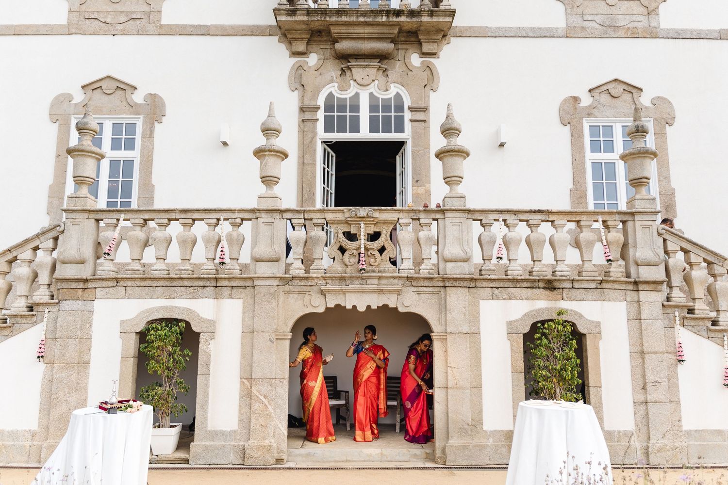 Stone balcony of elegant historic building with three figures in red attire.