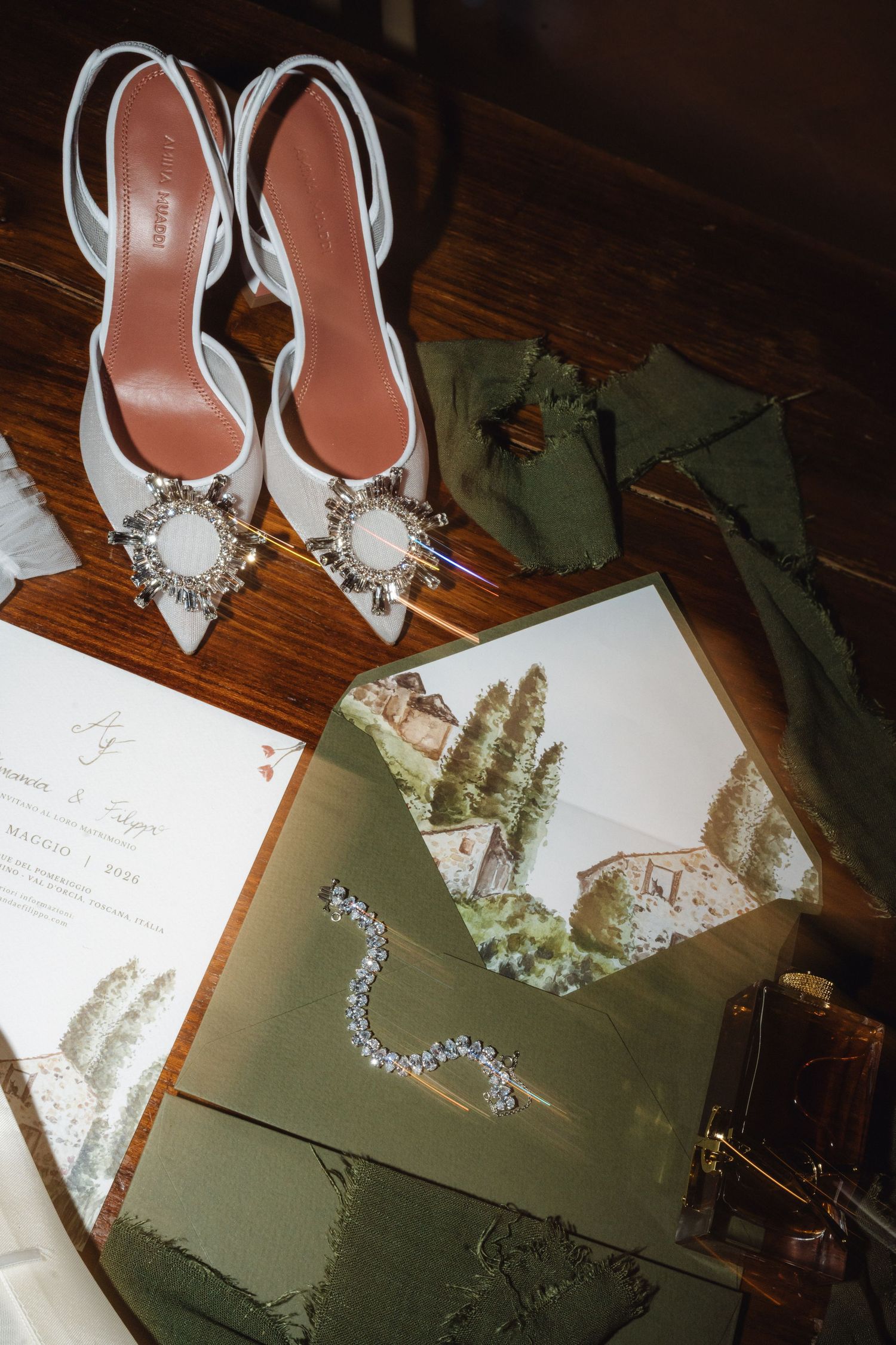 Elegant bridal flat lay with jeweled heels, diamond bracelet, green illustrated wedding invitation suite.