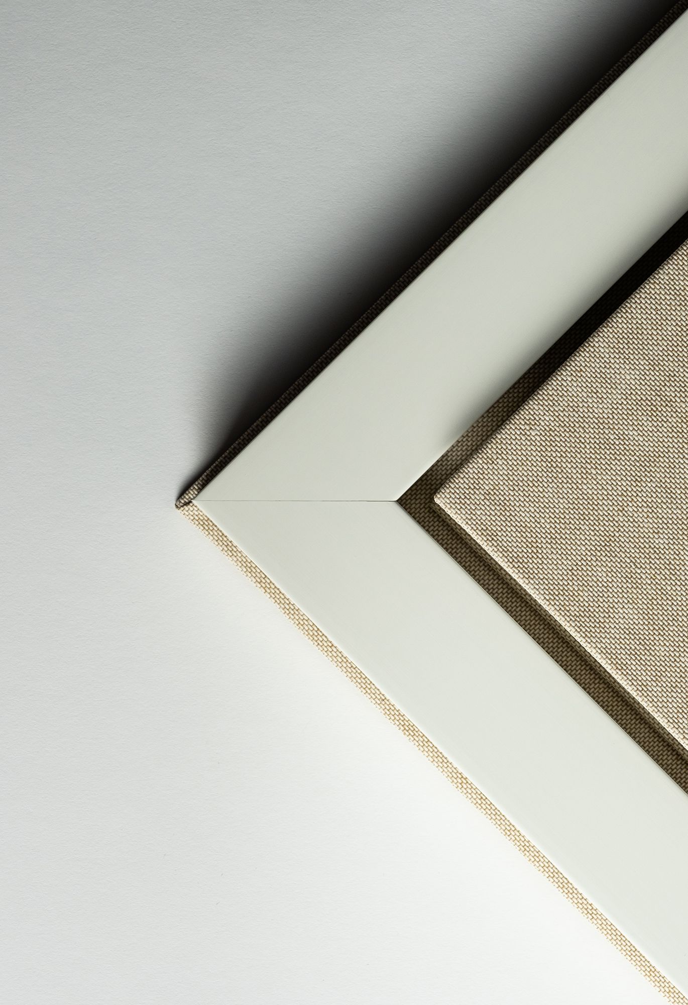 A series of minimalist white corners showing progressive cropping of a linen textured surface against a light background.