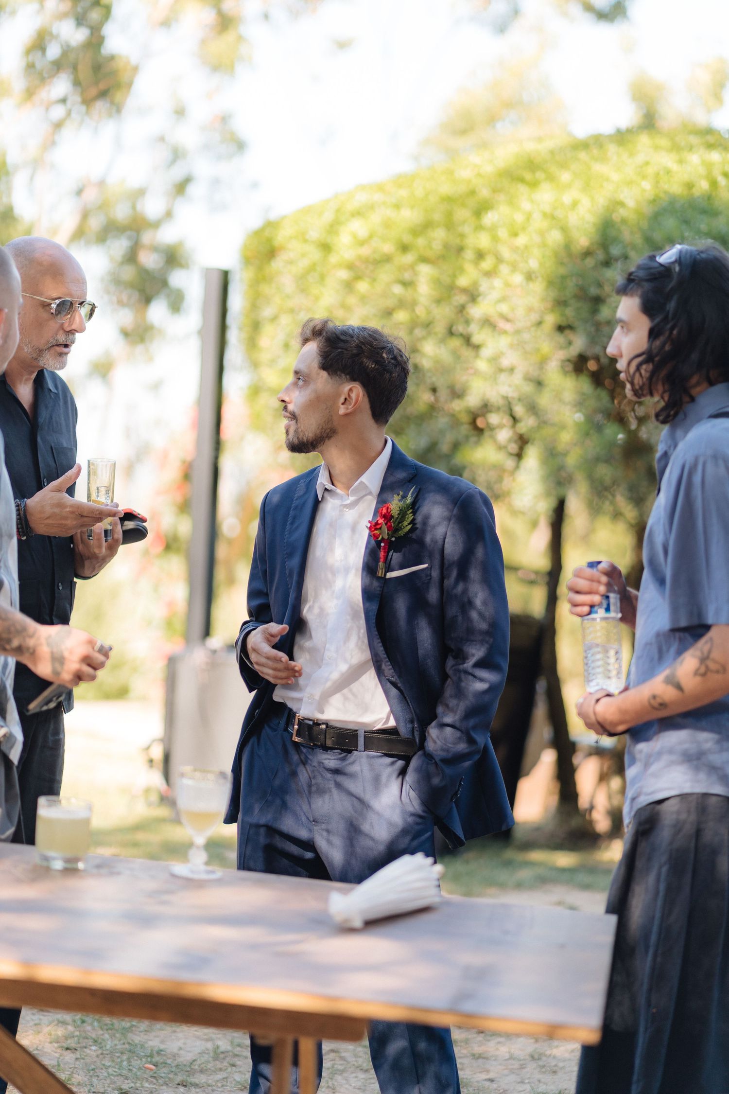 Group of guests having conversation at outdoor wedding reception.