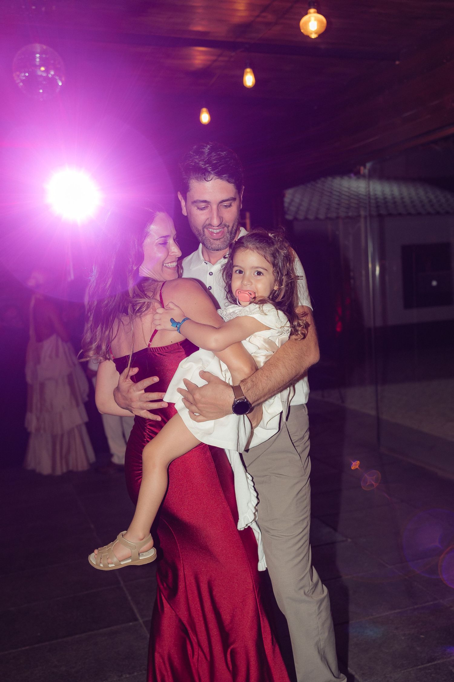 Couples dancing together under purple lighting at an evening wedding reception.