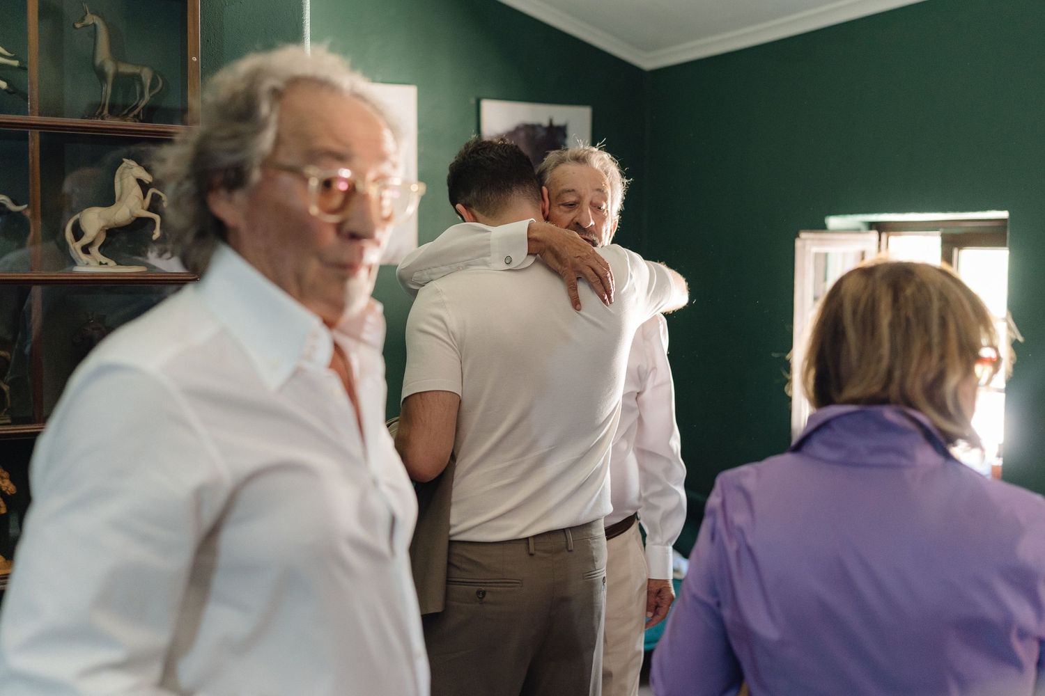 People interacting in a room with green walls and framed artwork.