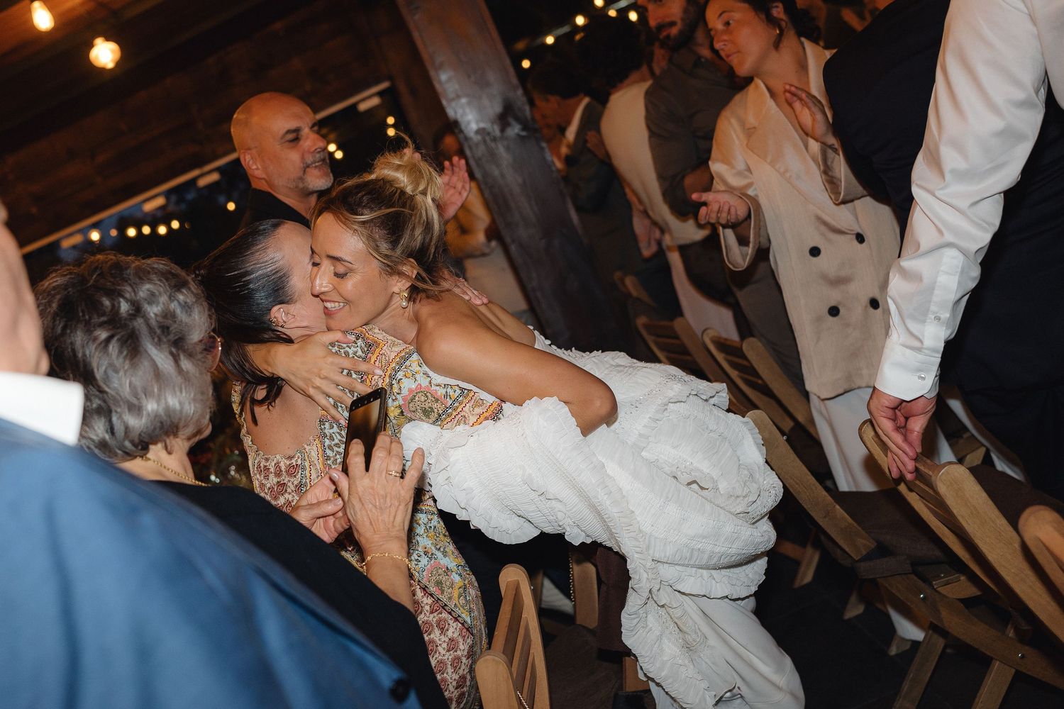 Guests dancing and embracing during an evening wedding reception celebration.