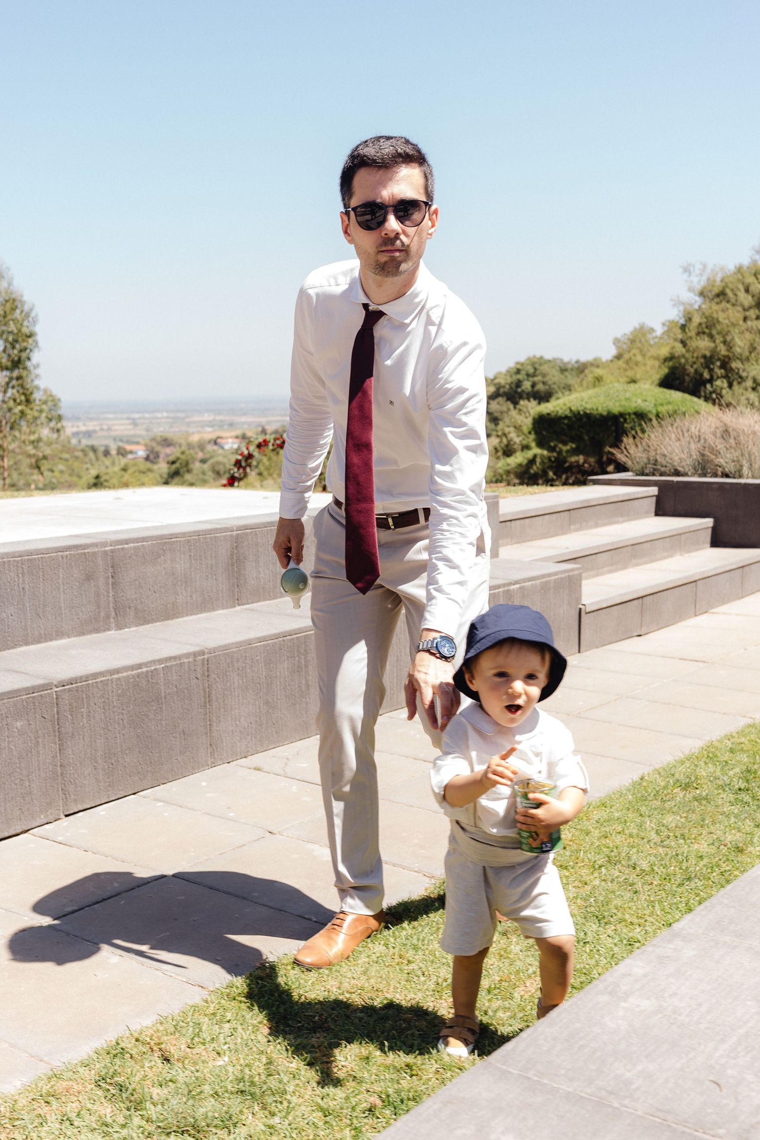 Formal outdoor portrait session on concrete steps against a bright blue sky.