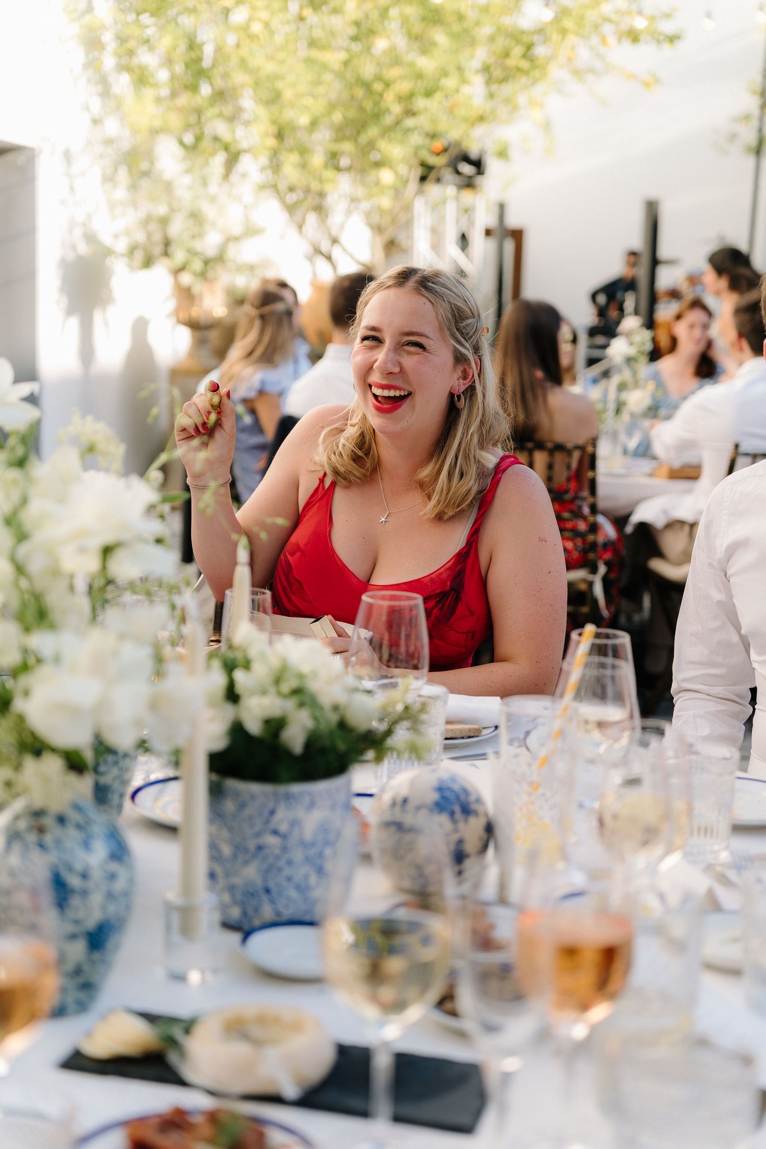 A guest in red enjoying dinner at an elegant outdoor table setting.