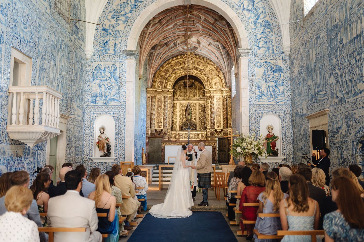 Wide view of Portuguese chapel interior with blue tile walls and gathered wedding guests.