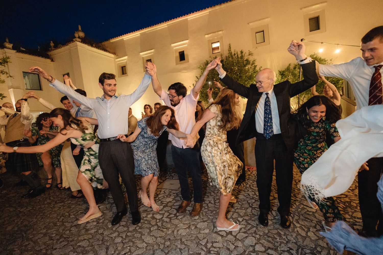 Wedding party members jumping and posing for a fun group photo outside.