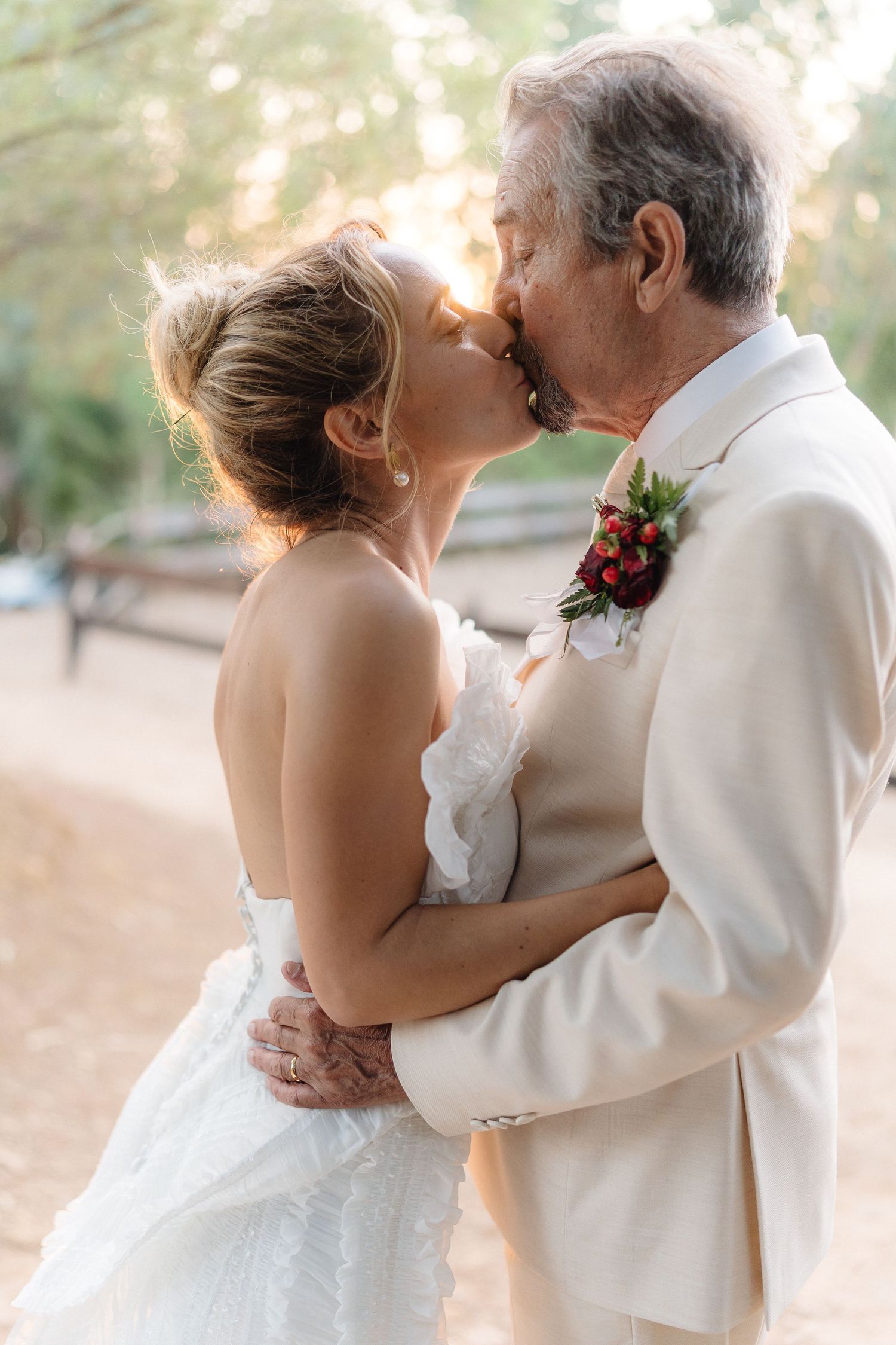 Wedding couple shares a tender embrace in white attire during their outdoor photo session.