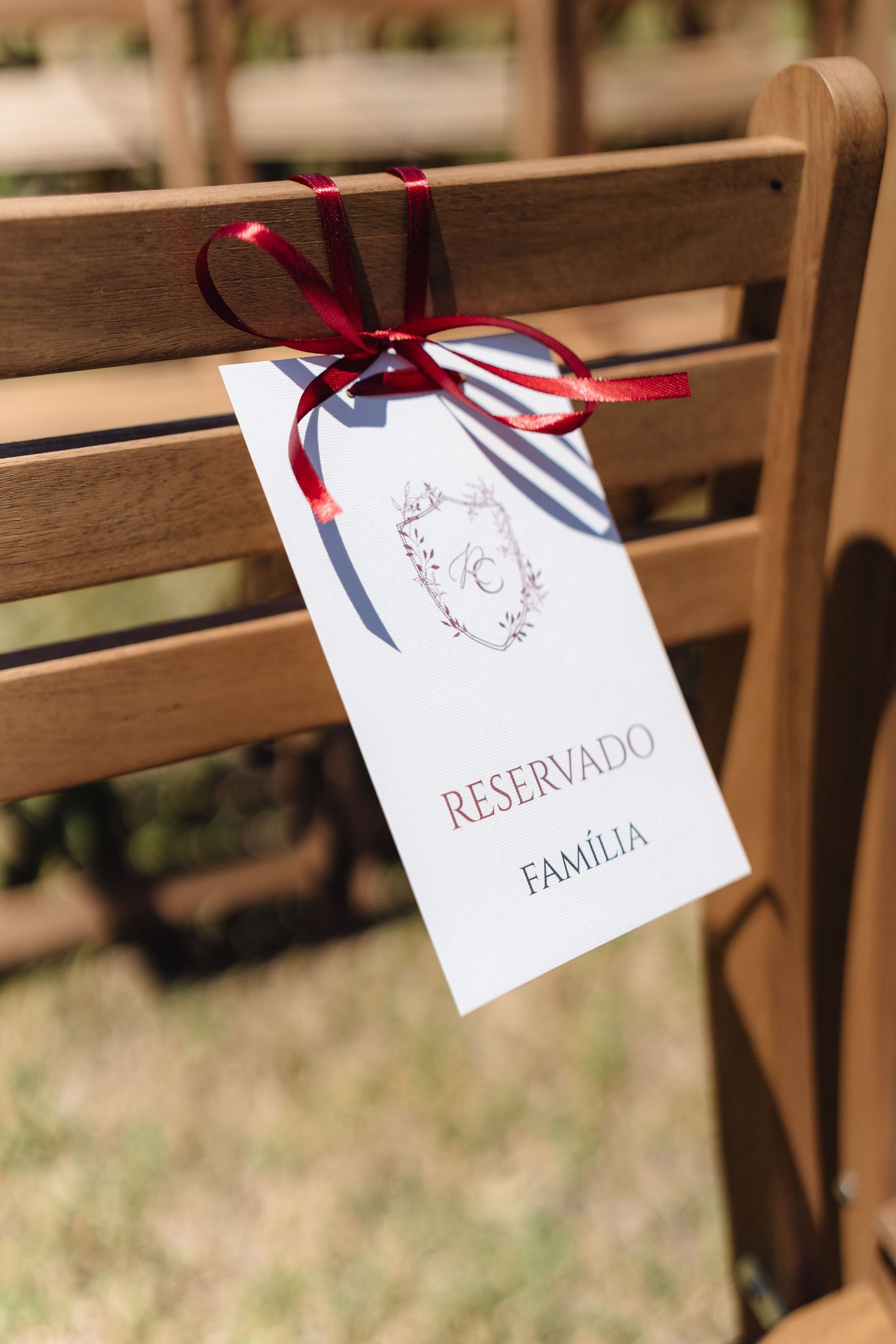 Wooden ceremony chairs decorated with white tags and red ribbons for reserved seating.