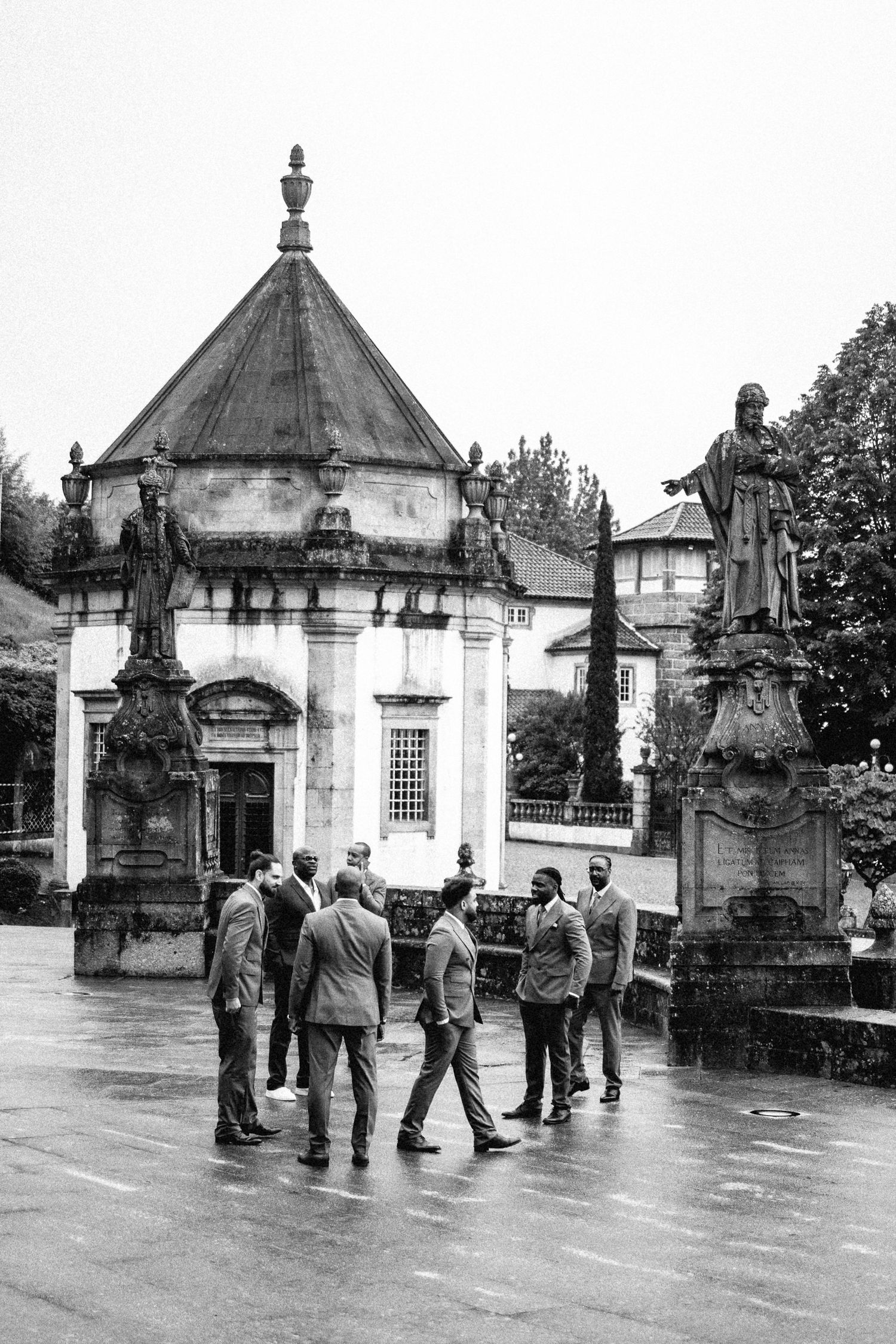 Black and white photo of tourists gathering outside historic domed building with statues.