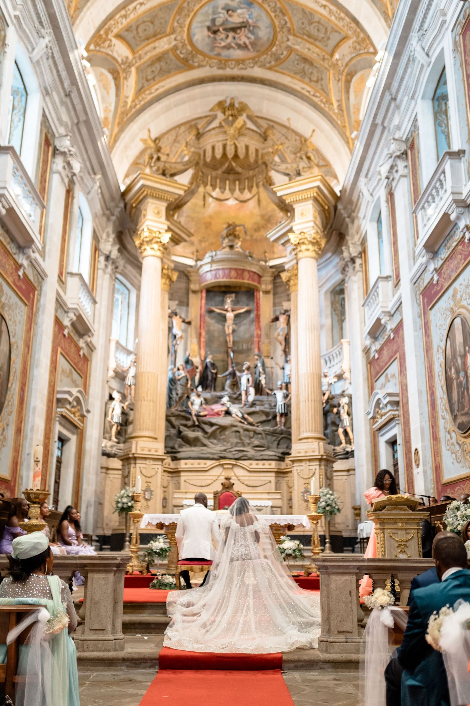 Ornate baroque church interior with white columns and golden details showcases a grand wedding ceremony setup.
