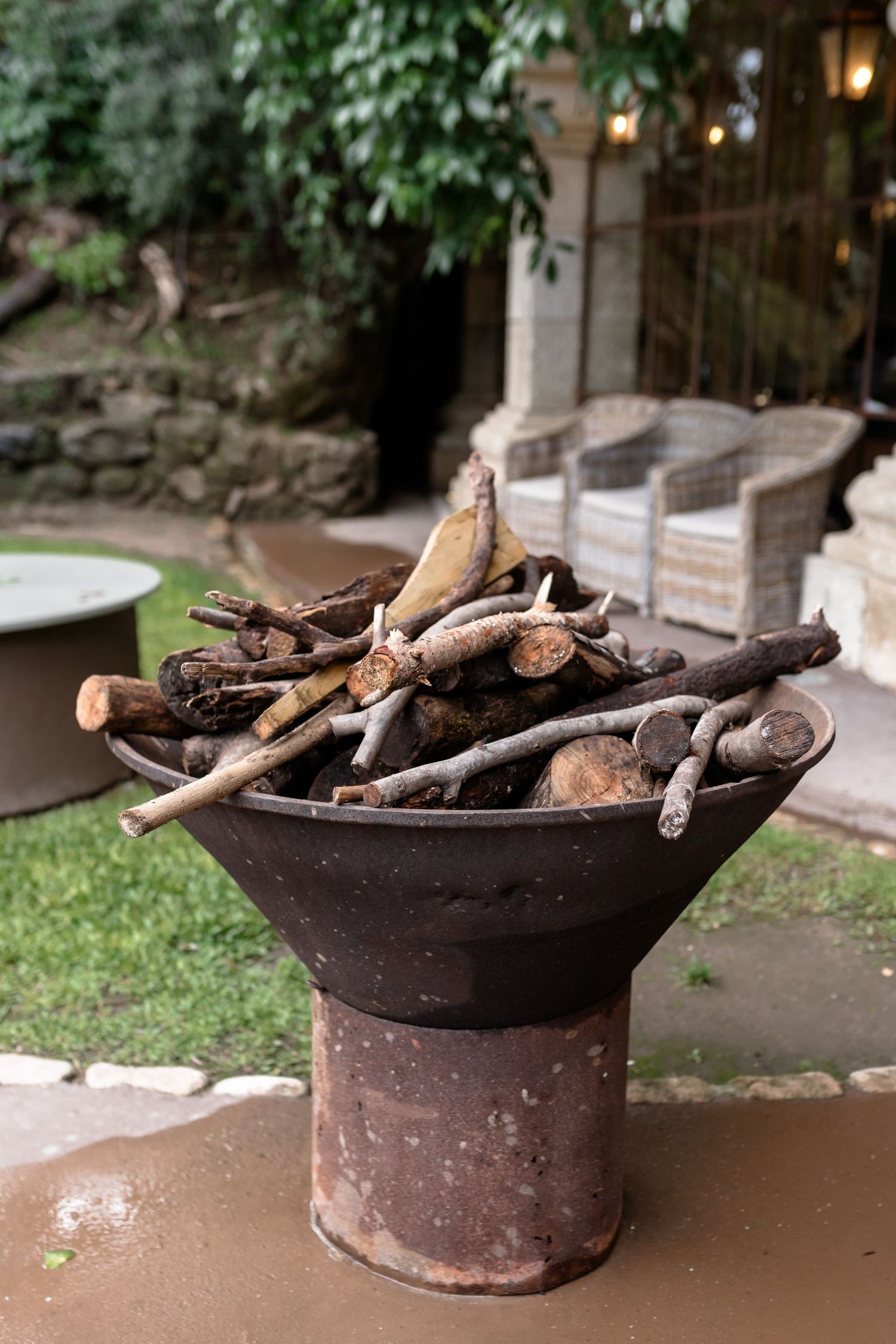 Fire pit filled with wooden logs in outdoor garden setting.