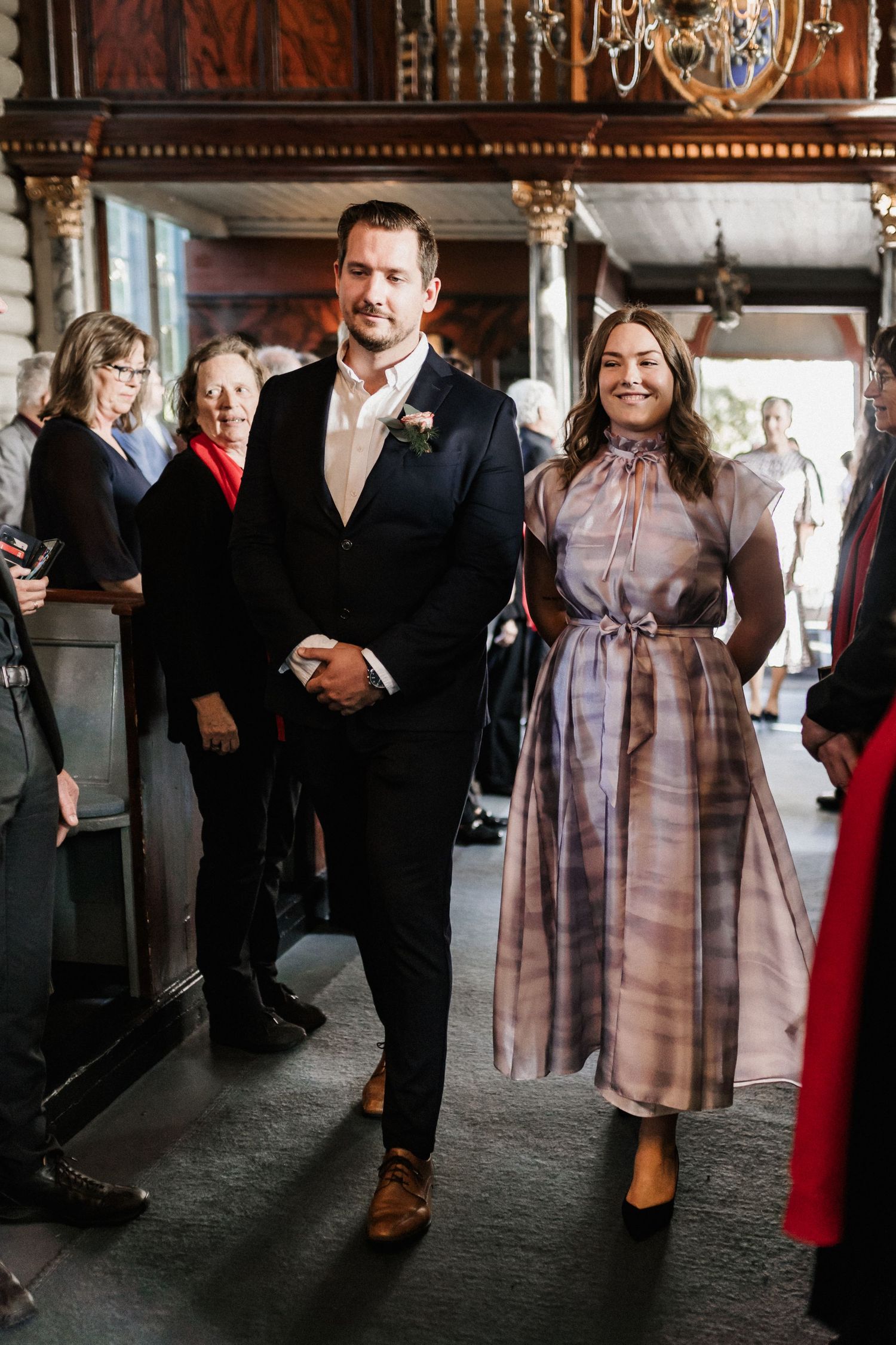 Wedding celebration inside an ornate venue with guests mingling and dancing.