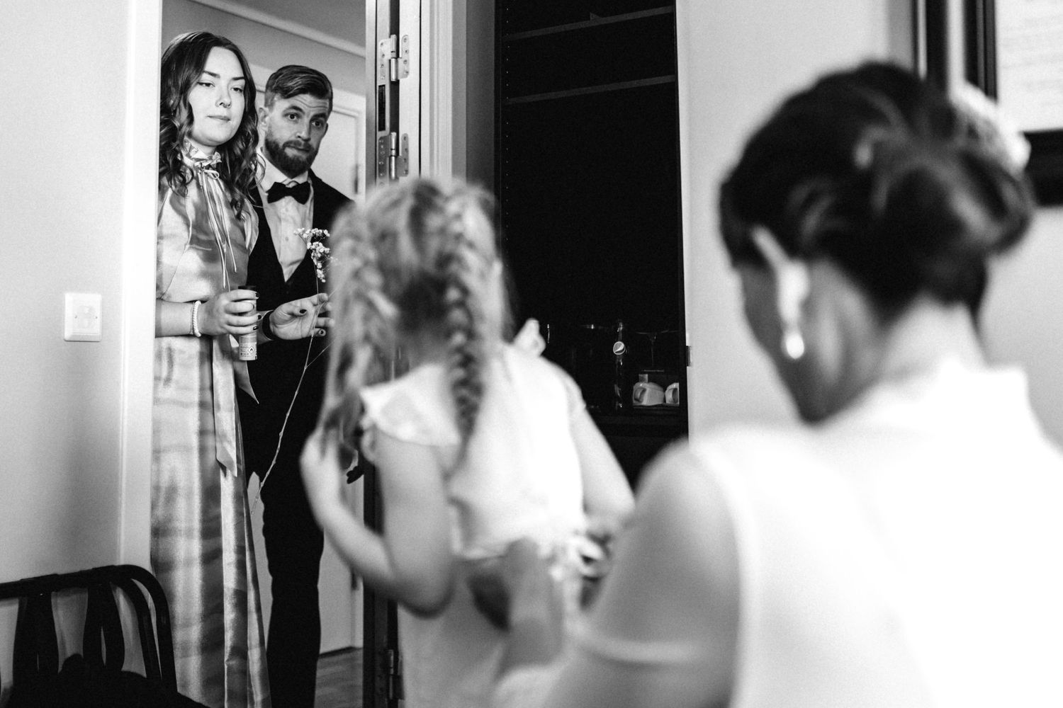 A group gathers in black and white formal attire during what appears to be a wedding preparation.