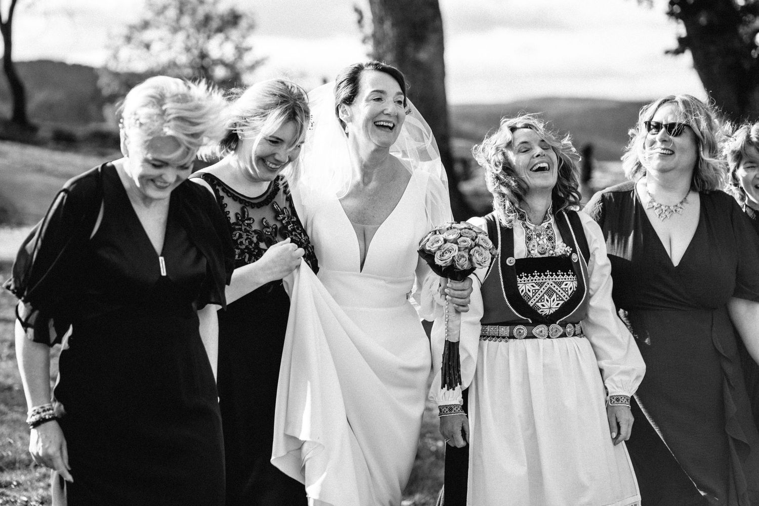 Black and white photo of wedding guests sharing joyful moments outdoors.