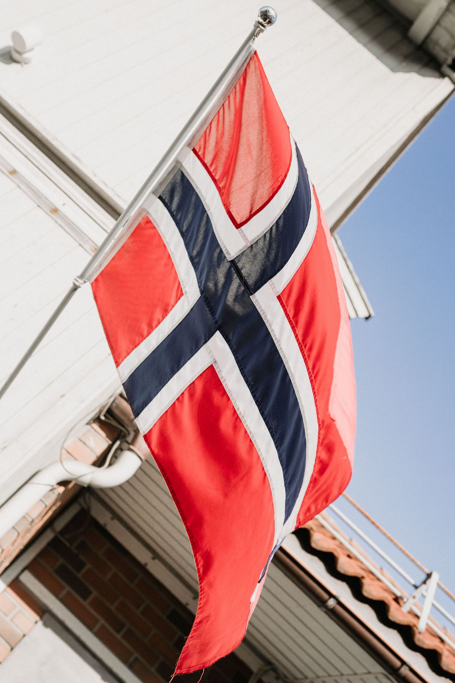 Norwegian flags waving against a blue sky in a series of photographs.