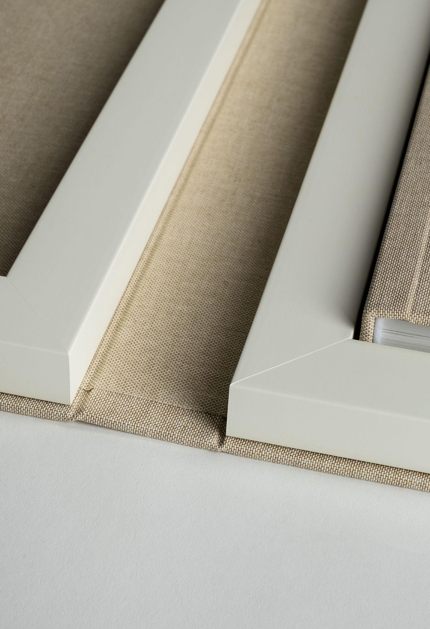 Close-up of beige linen canvas stretched over white wooden frames showing textural details and clean lines.