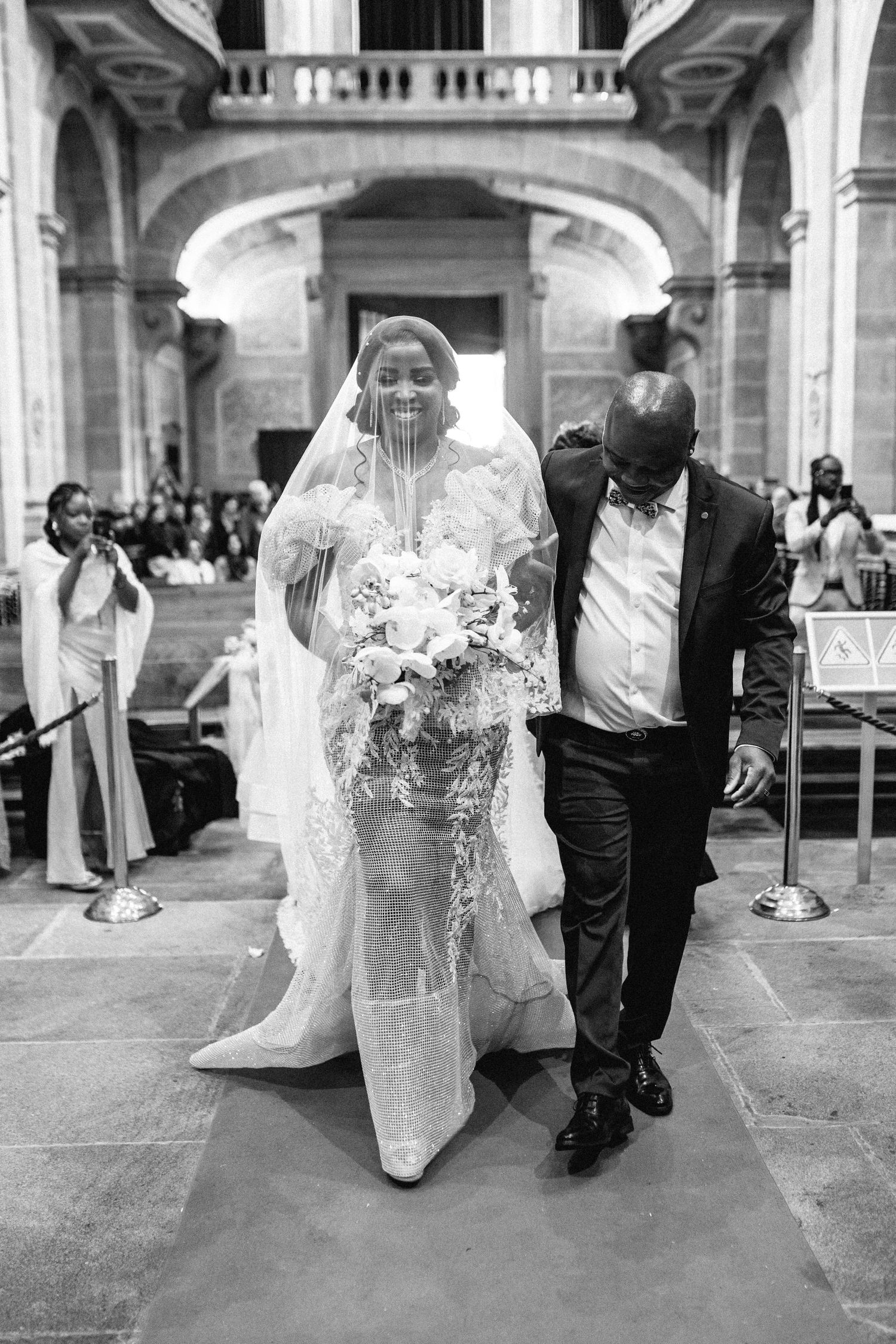 Black and white wedding photos showing the bride and groom walking together through an elegant archway.