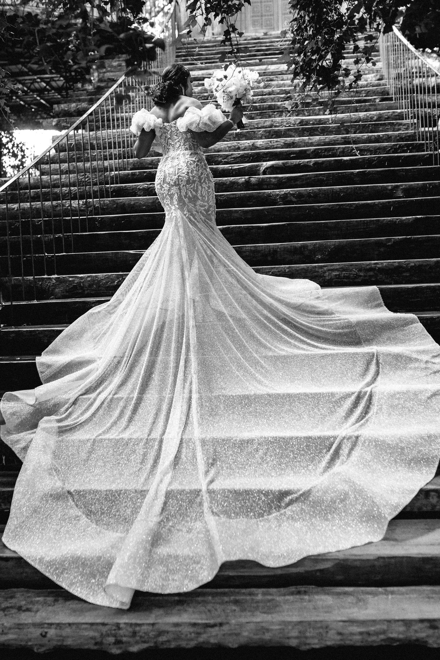 Dramatic black and white photos of flowing wedding dress on stone steps.