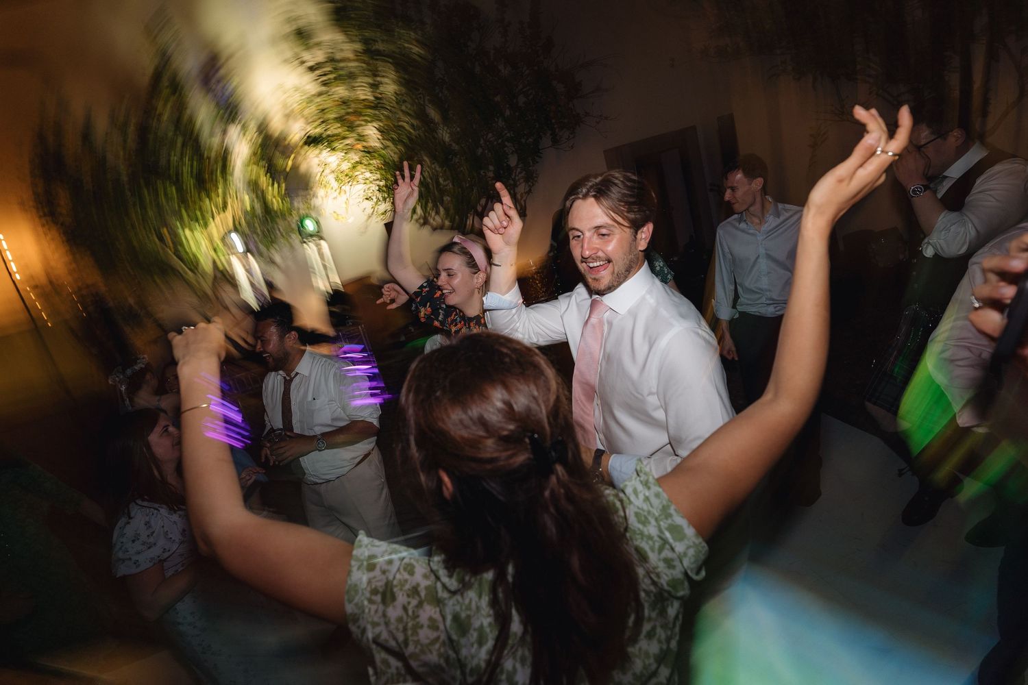 Lively dance floor scene with party guests celebrating under ambient lighting.
