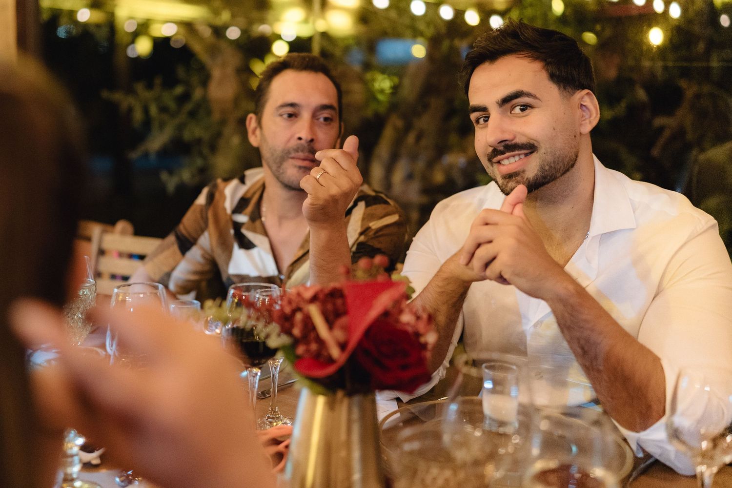 Diners engaged in conversation at an evening reception with warm lighting and elegant table settings.