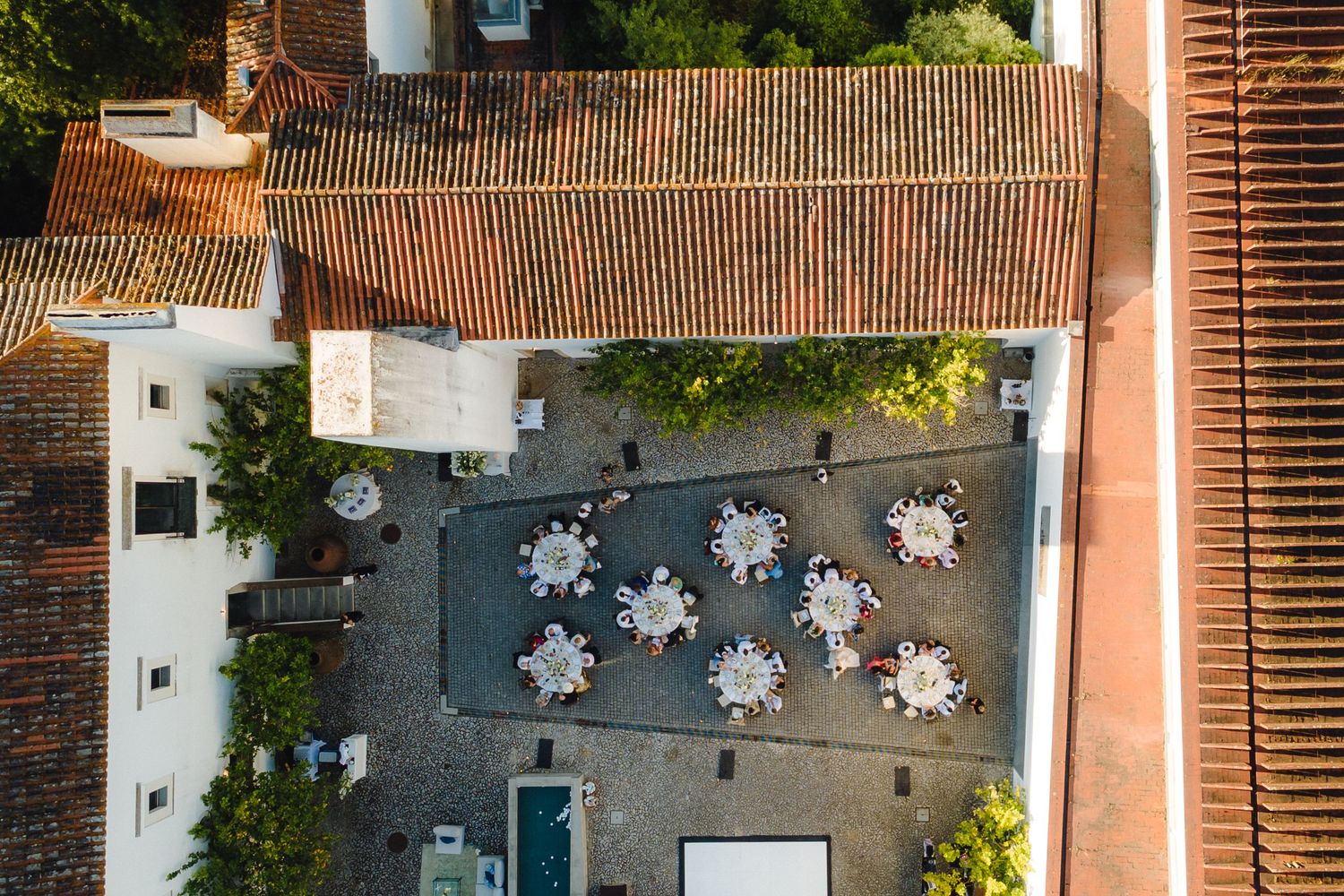 Aerial view of white buildings with terracotta roofs and decorative hanging lights.