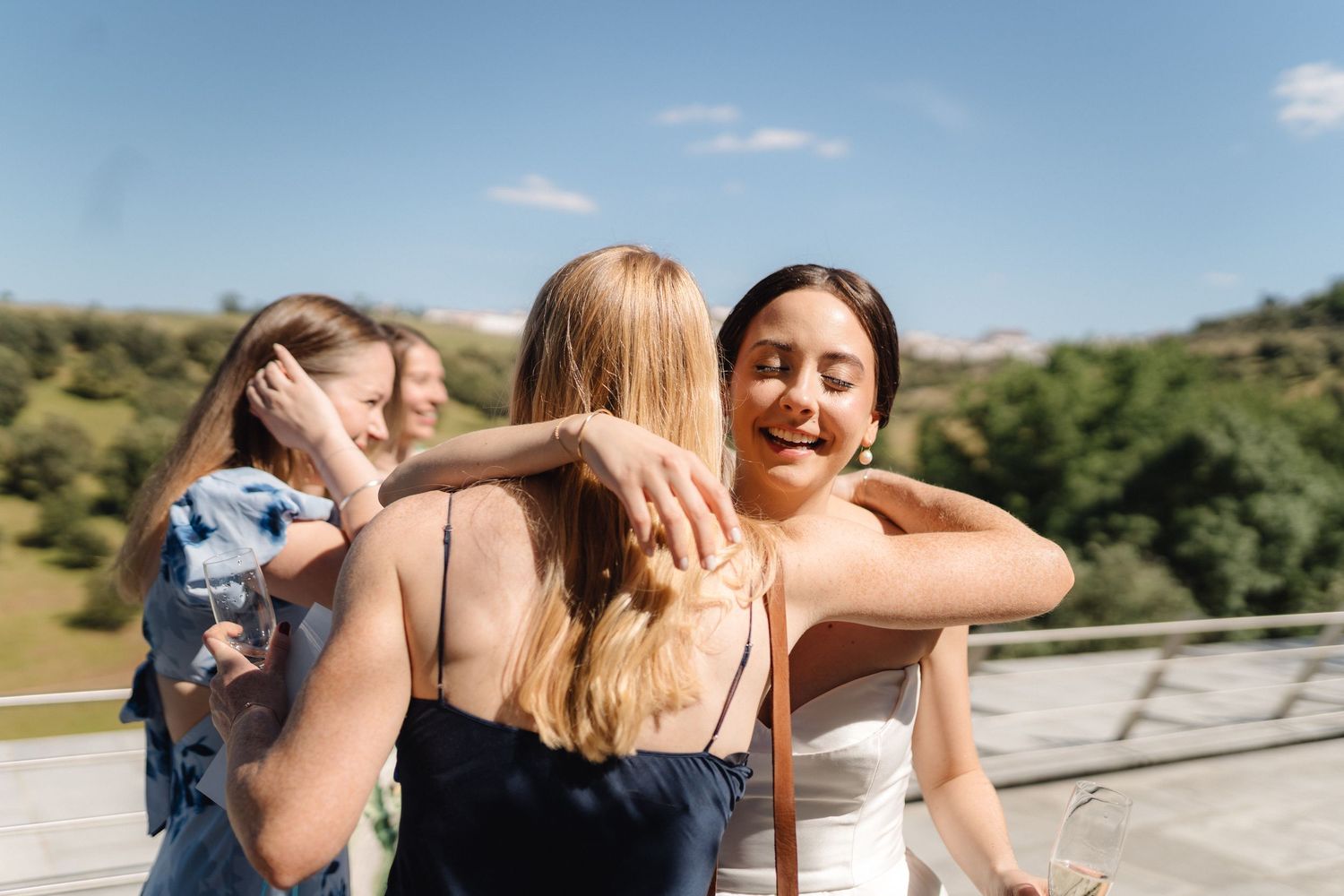 Celebratory hugs shared during an outdoor event with rolling hills in the background.
