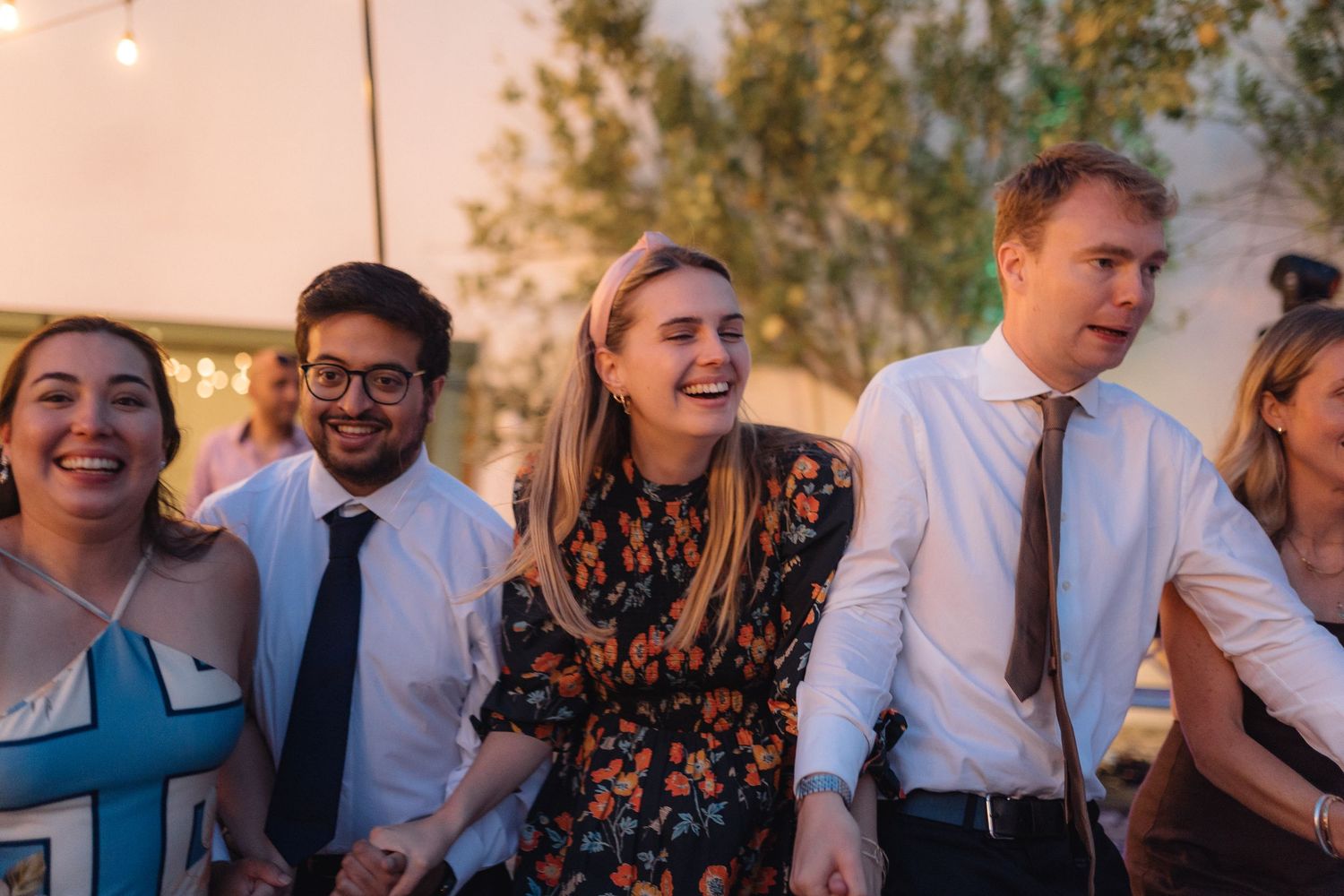 Party guests mingling and laughing together at a sunset celebration.
