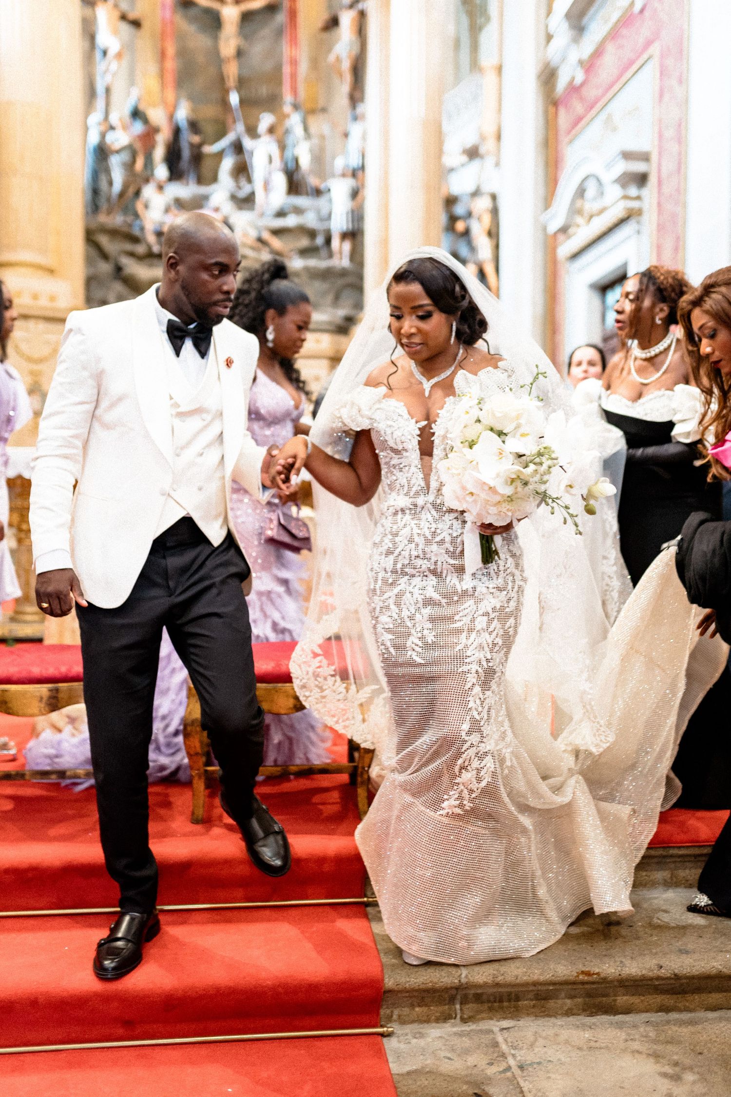Wedding couple dancing energetically on a red carpet in a church with ornate decor.