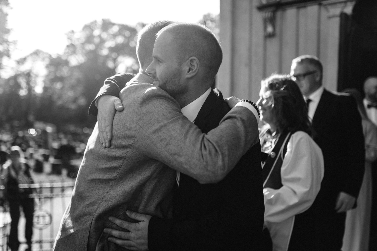 Two people share a heartfelt hug outside during a wedding celebration.