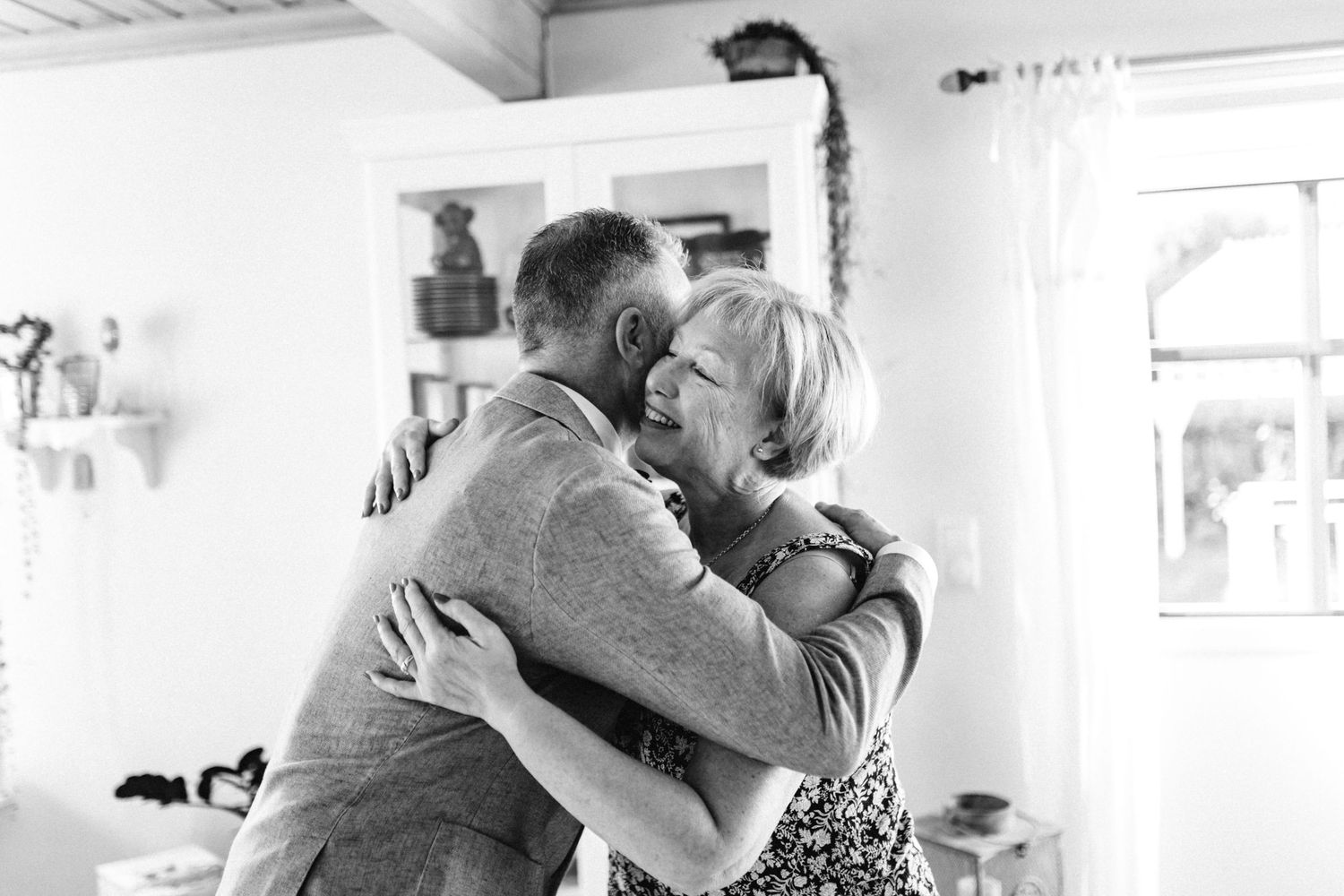 Multiple frames showing tender embraces between people in a light-filled domestic interior space.
