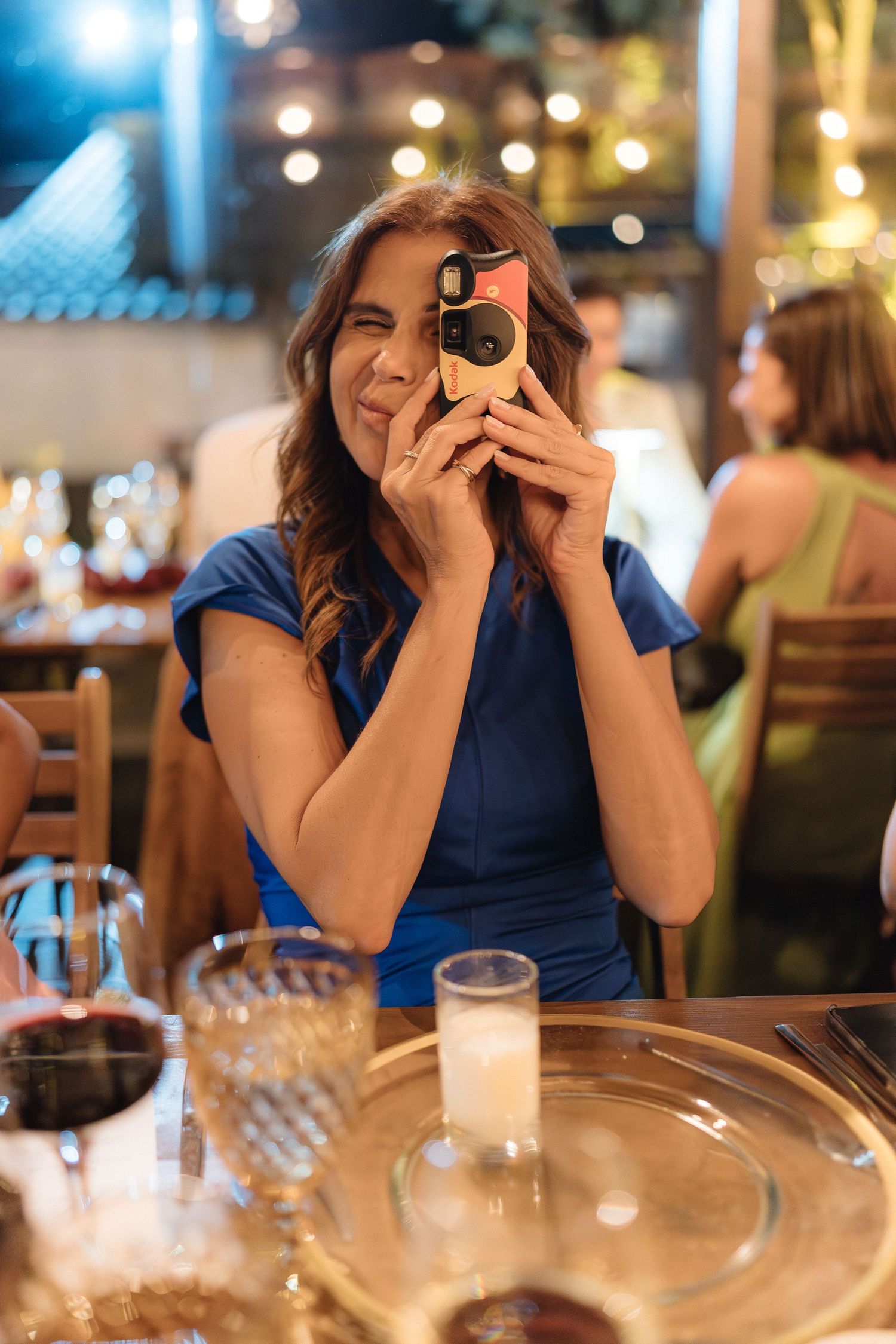 Guest taking photos with phone during an elegant dinner reception with blue lighting.