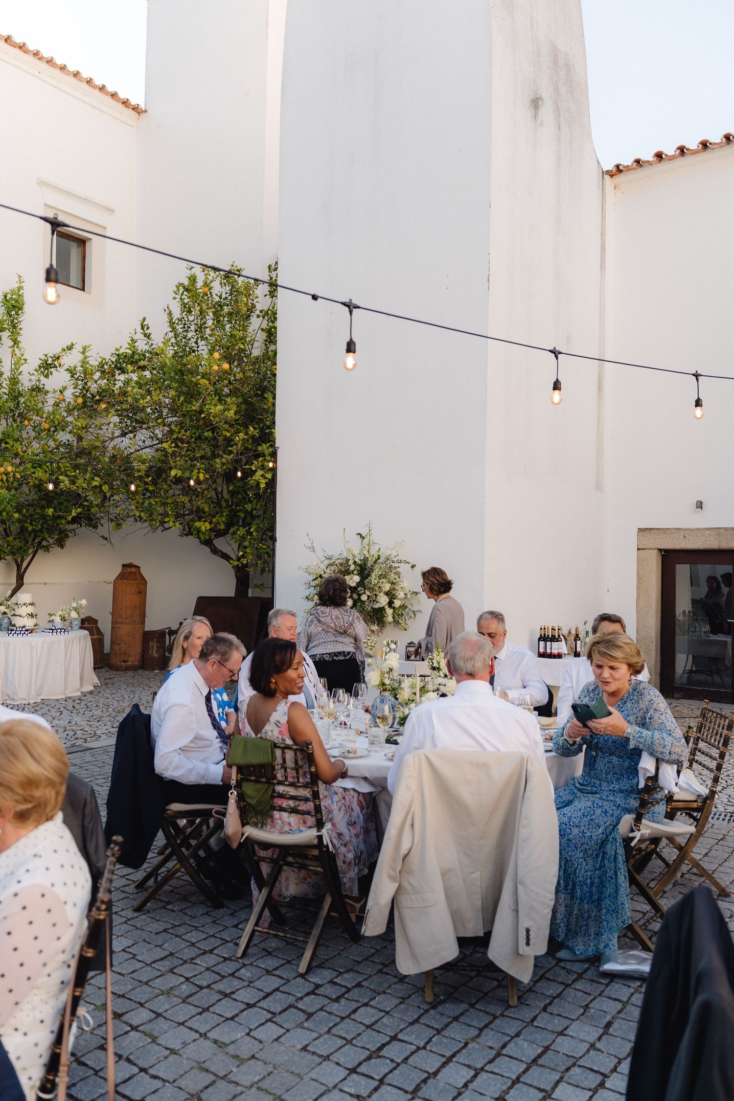 Evening wedding reception with string lights and white architecture creating an intimate atmosphere.