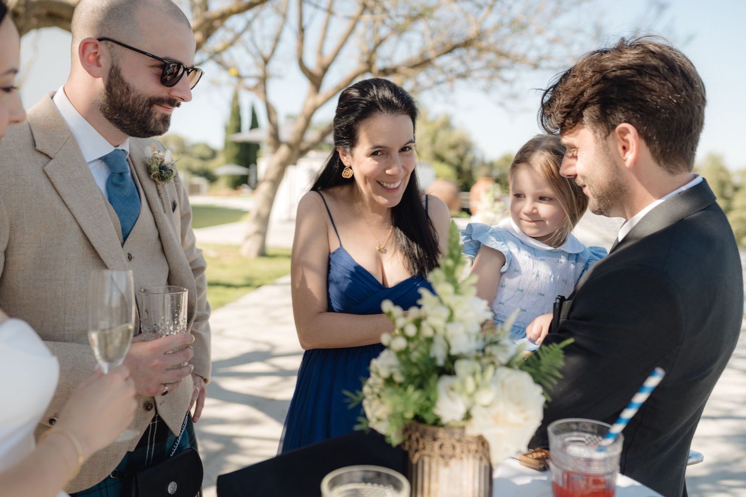 Wedding guests chat and hold drinks during an outdoor reception.