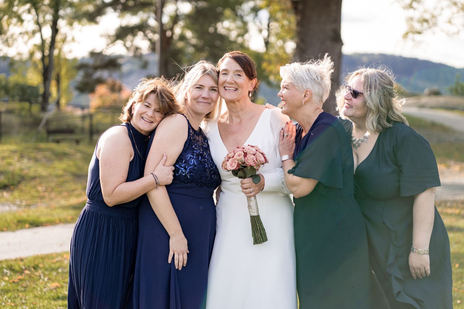 Wedding party poses outdoors in navy blue and white attire during golden hour celebration.