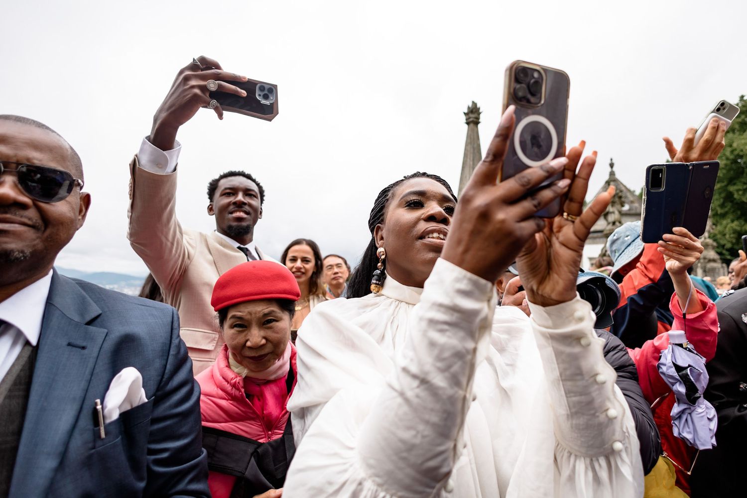 Excited wedding guests capturing photos and videos on their phones during celebration.