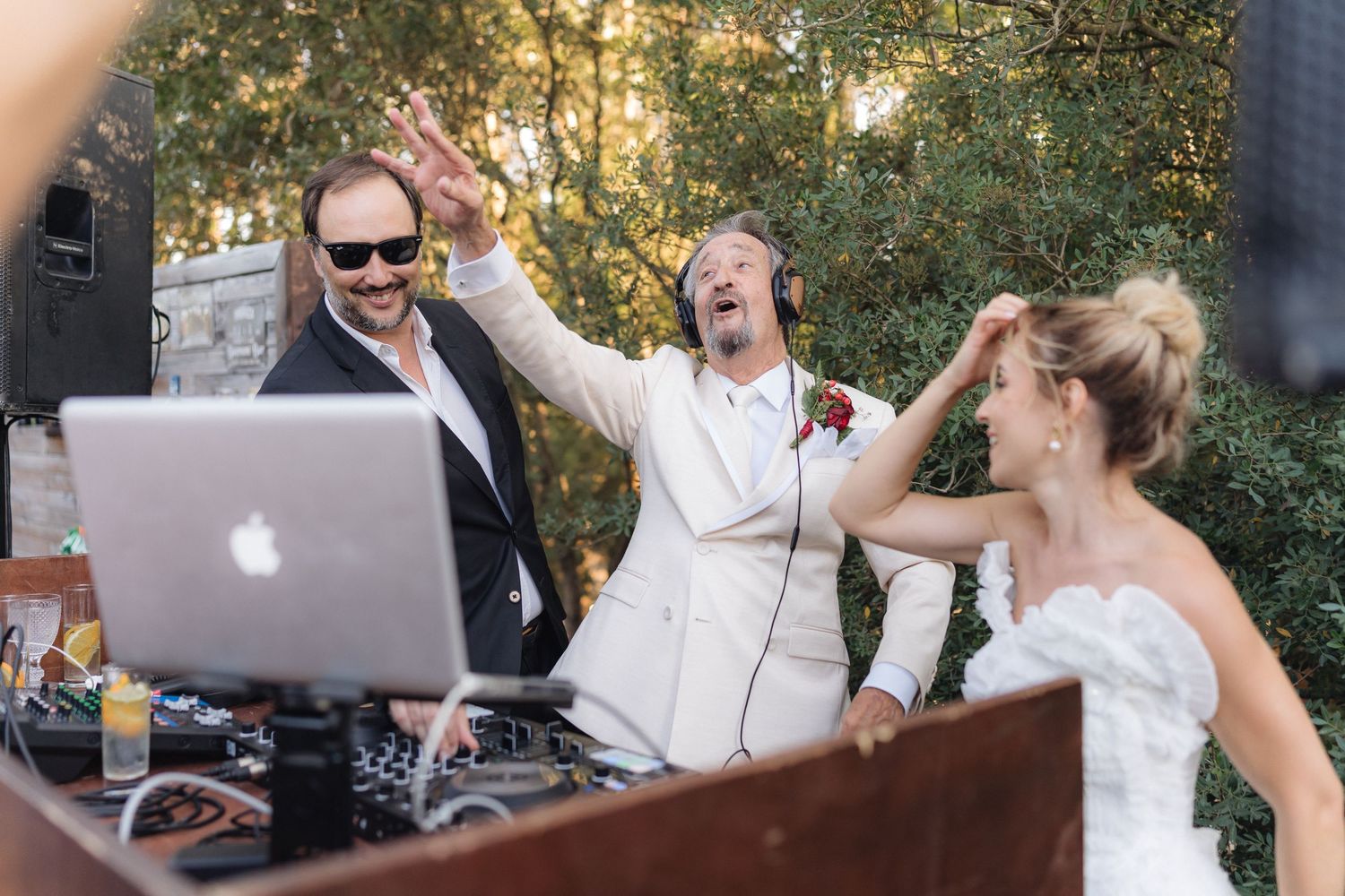 Guests enjoying music and dancing at outdoor wedding reception with DJ setup.