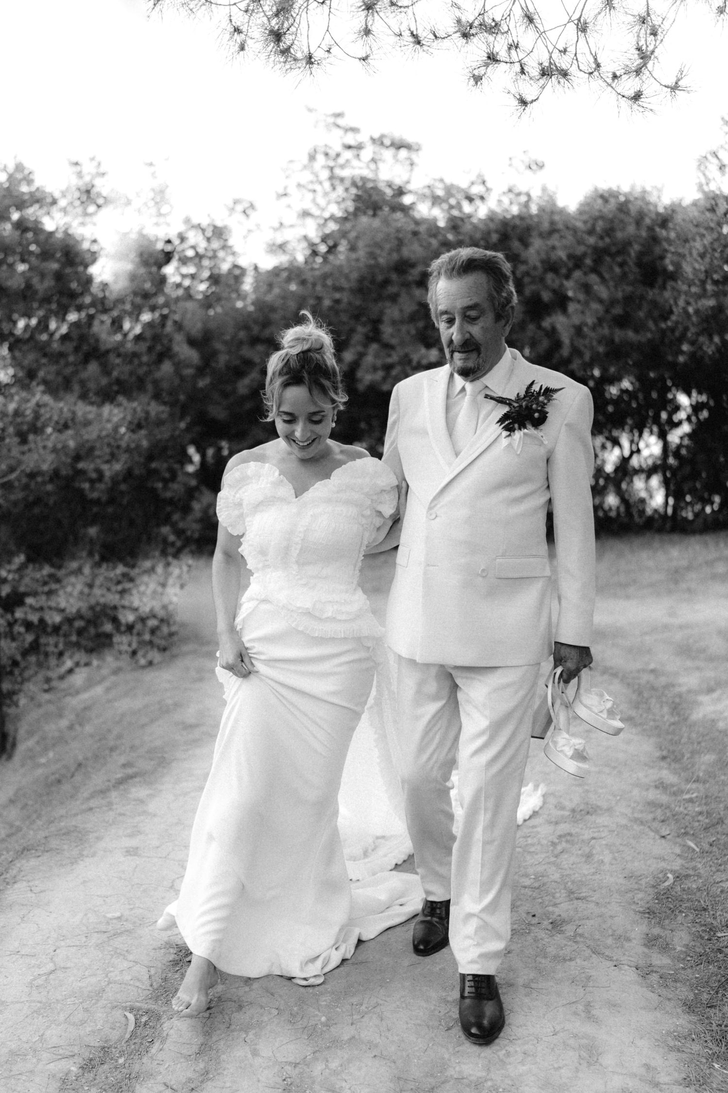 Black and white wedding photo showing a couple walking together on a garden path.