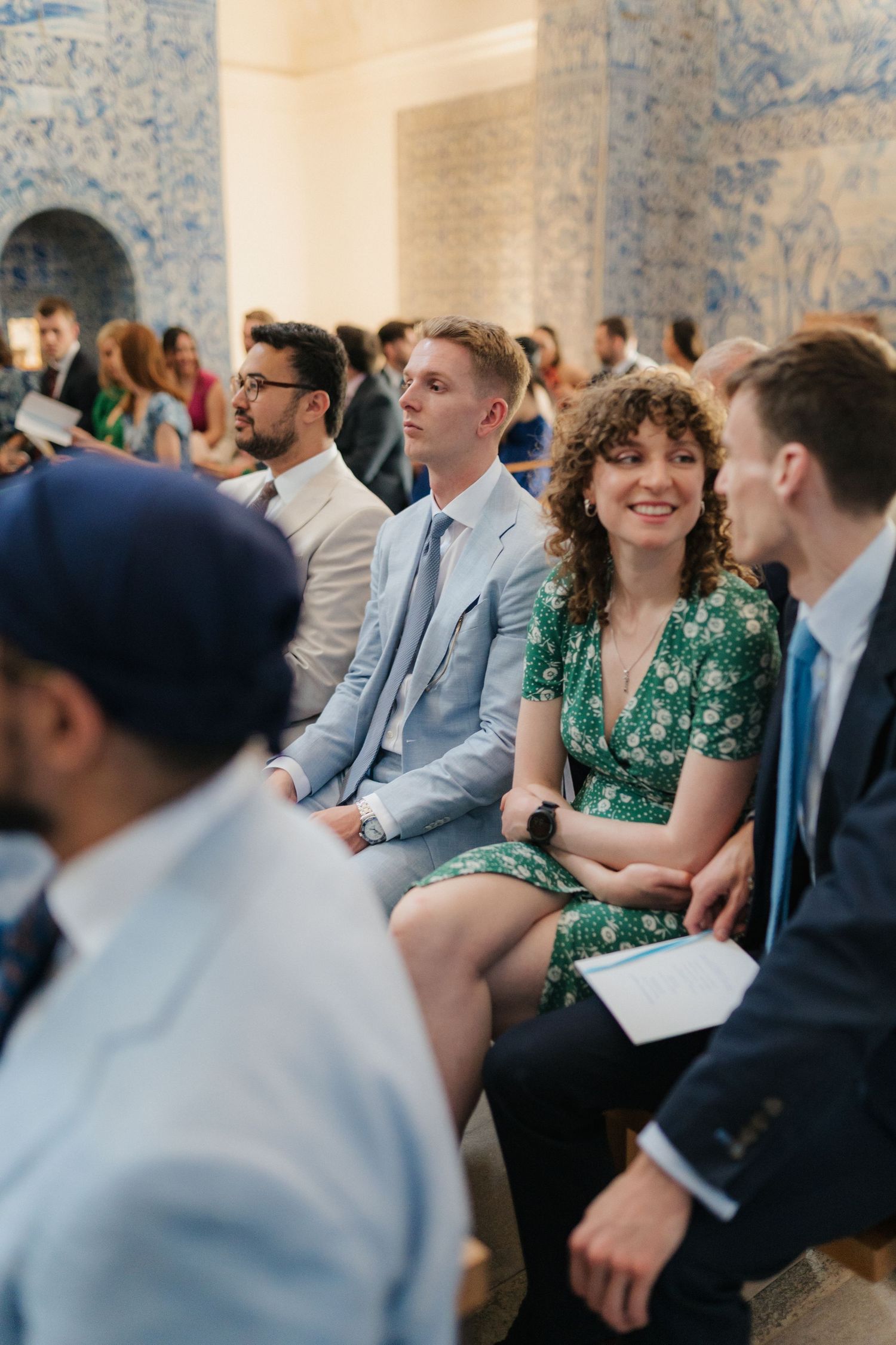 Wedding guests seated in rows with blue wallpaper and elegant decor.