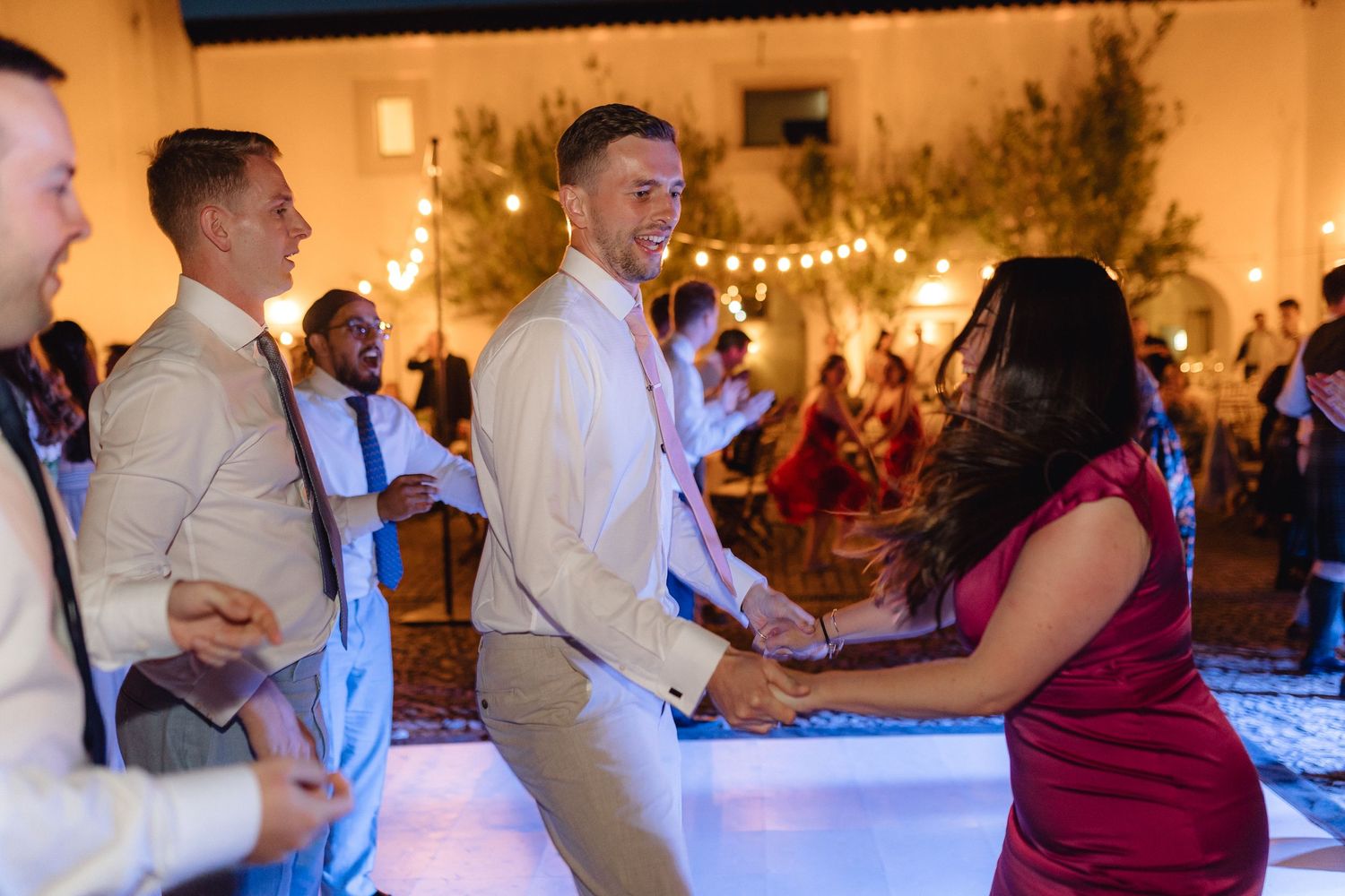 Couples dancing together at a wedding reception with warm ambient lighting.