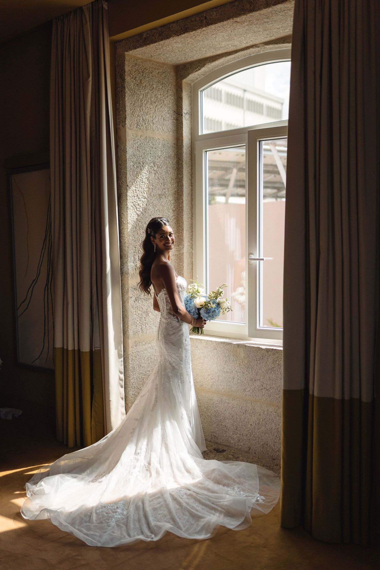 Elegant bridal poses in natural window light with flowing white gown.