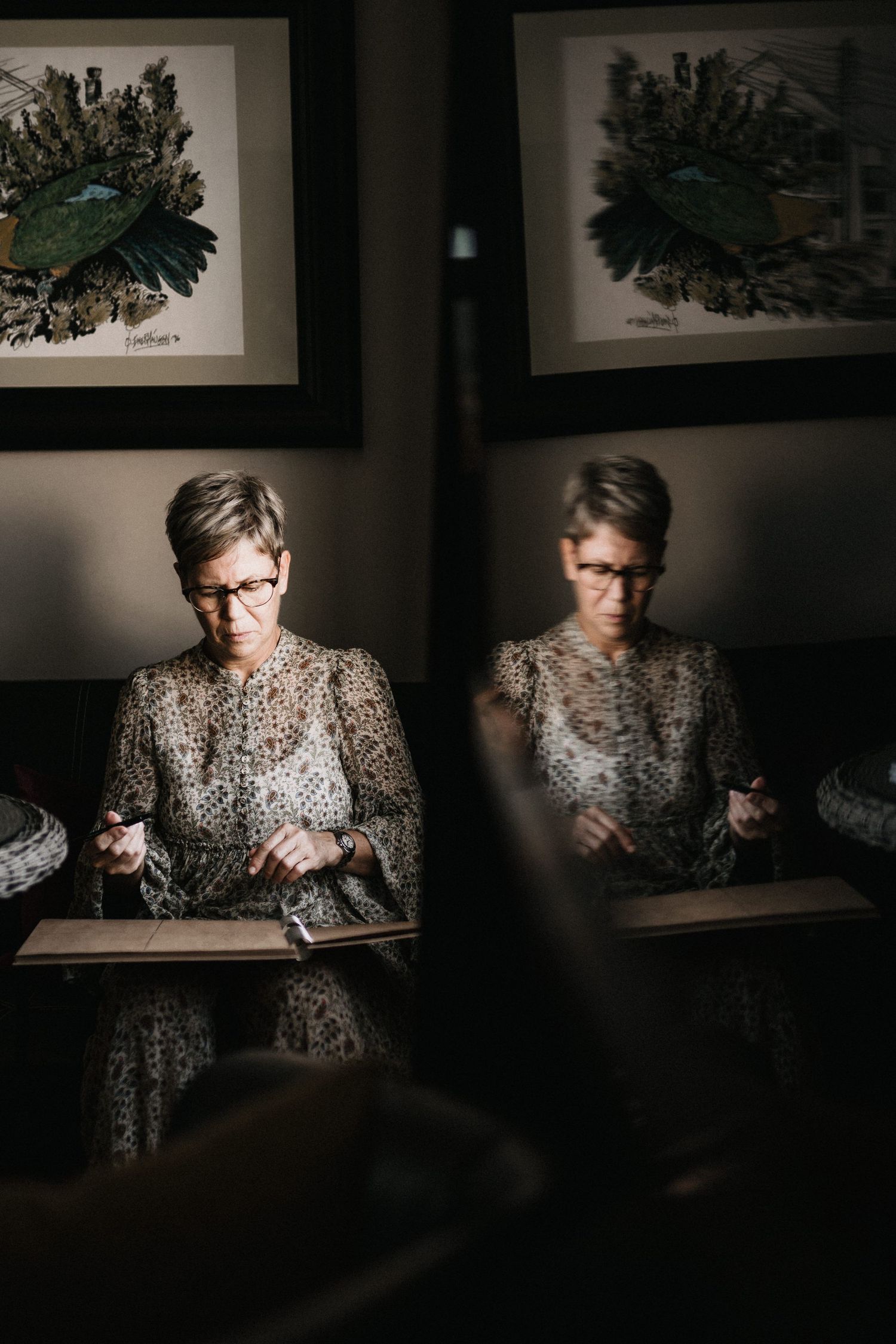 Moody portrait in low light showing person in patterned clothing examining something.